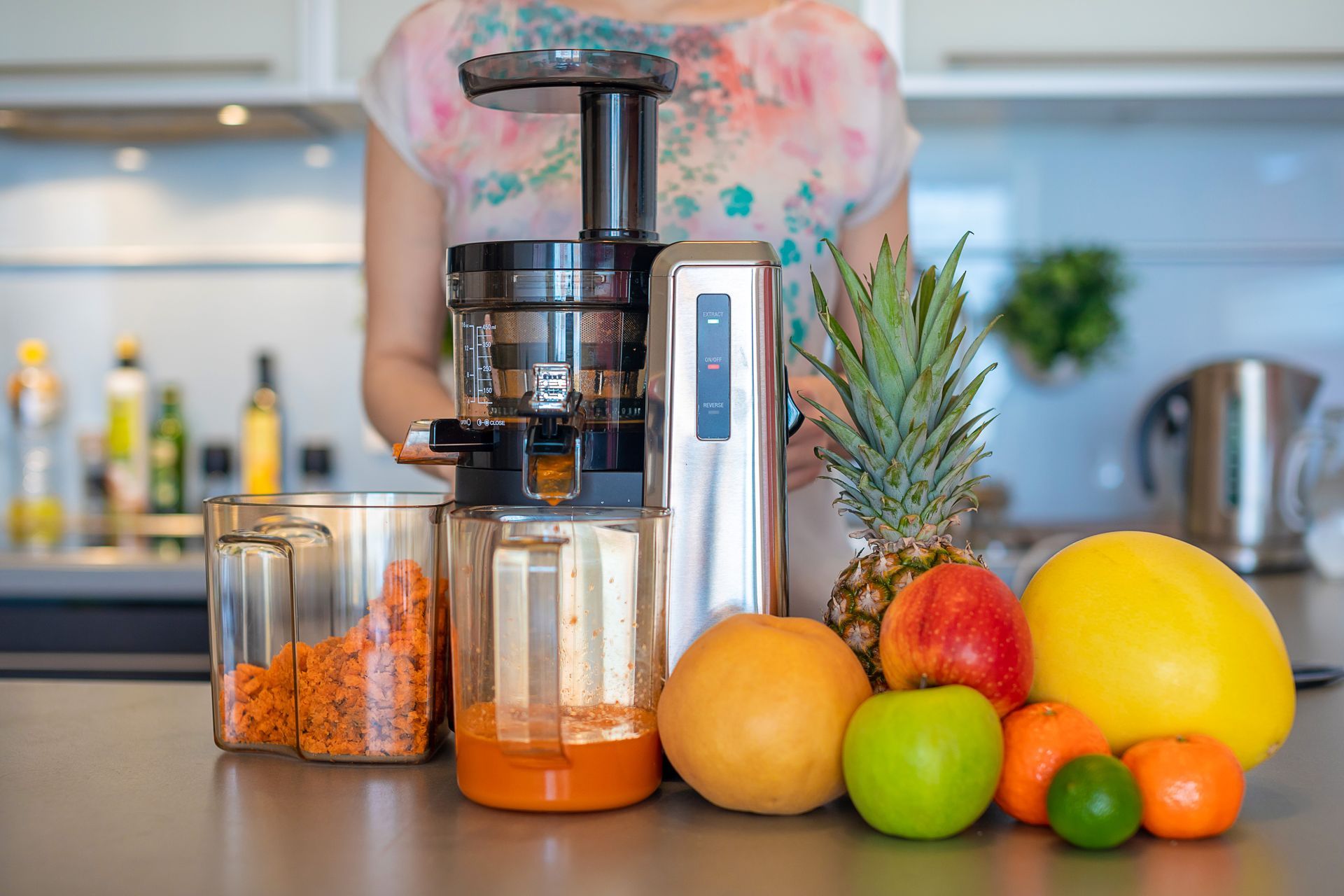 A woman is using a juicer to make juice in a kitchen.