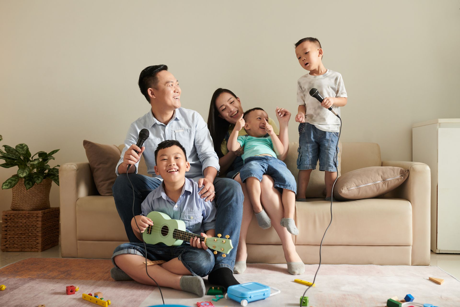A family is sitting on a couch in a living room singing into microphones.