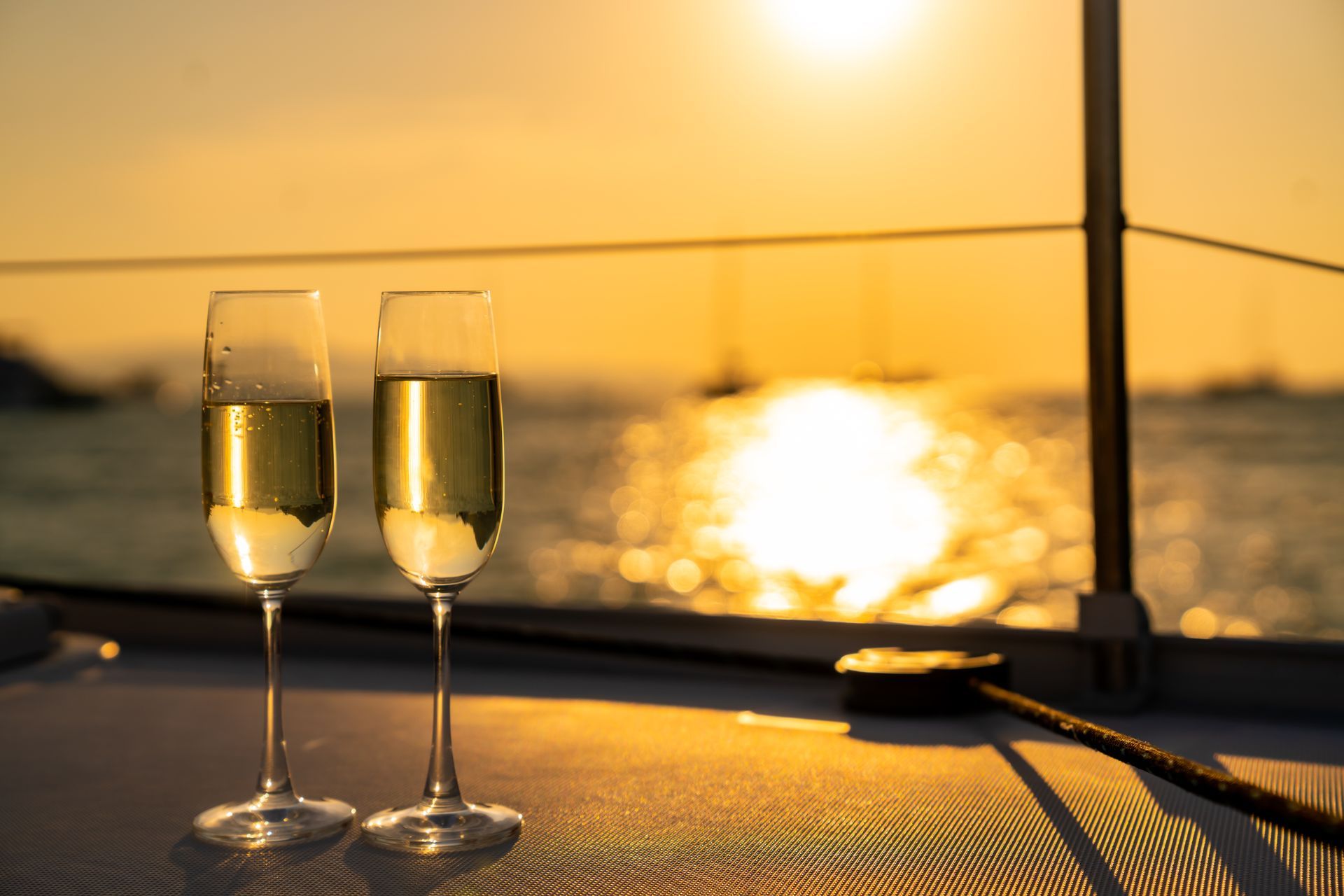 Two glasses of champagne are sitting on a boat at sunset.