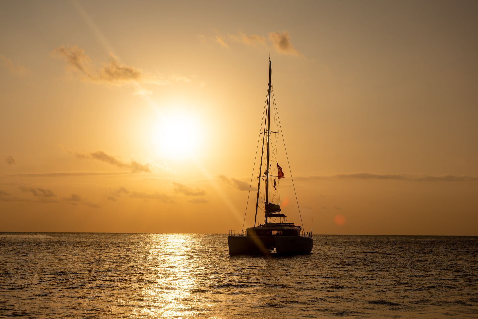 A sailboat is floating on top of a body of water at sunset.