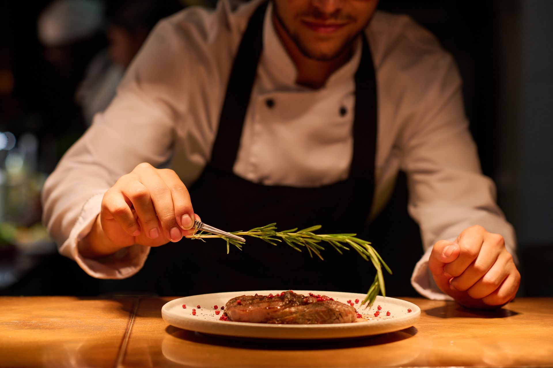 A chef is cutting a piece of meat on a plate.