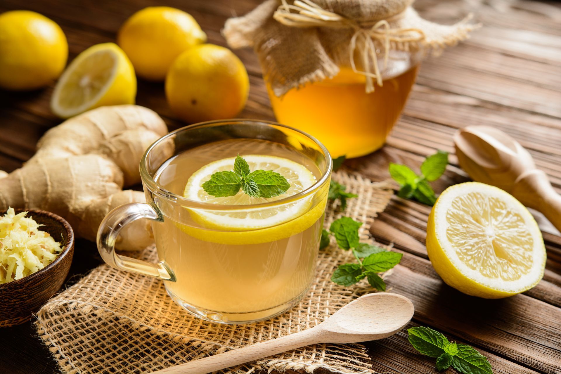 A cup of tea with lemon , ginger and honey on a wooden table.