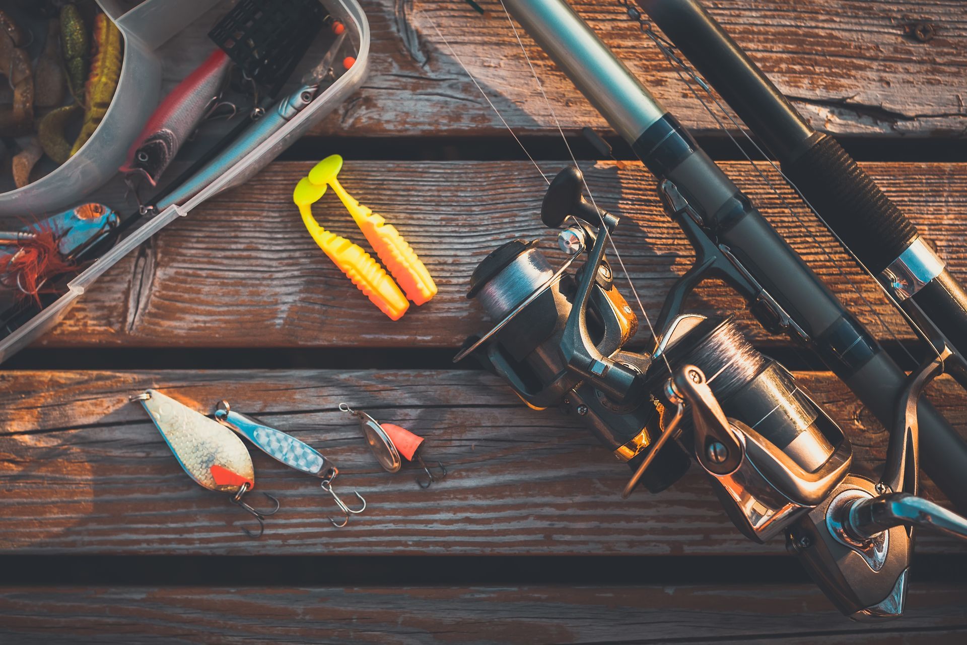 A fishing rod and reel are sitting on a wooden table.