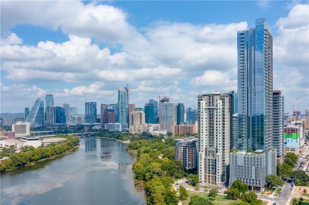Austin, Texas skyline with river and high-rise buildings under a cloudy sky.