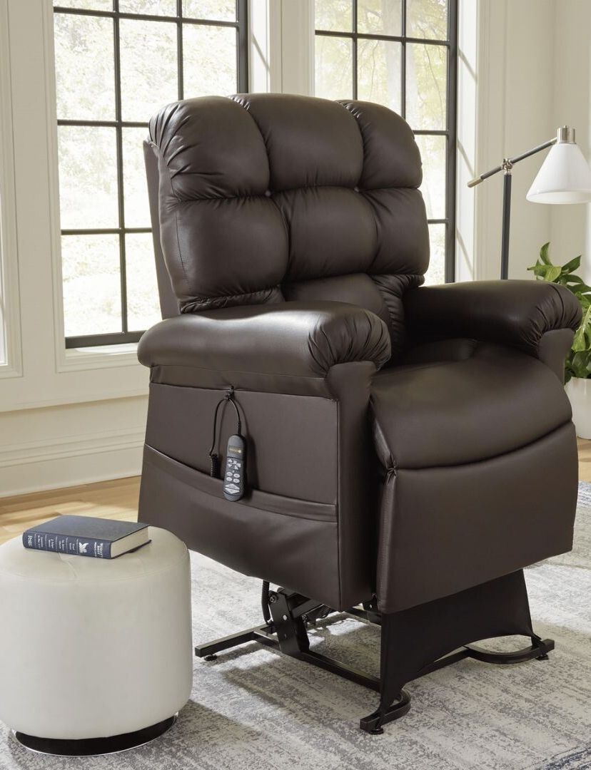 A brown leather recliner is sitting next to a white ottoman in a living room.