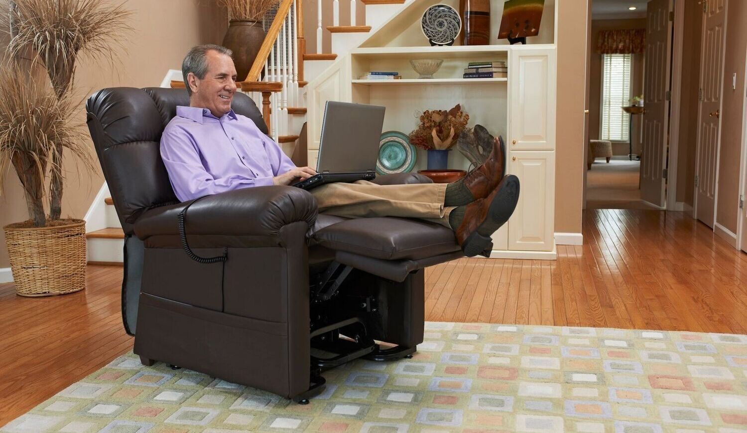 A man is sitting in a recliner using a laptop computer.