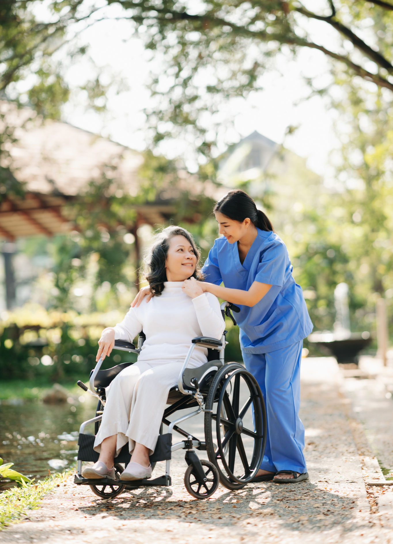 A nurse is helping an elderly woman in a wheelchair.