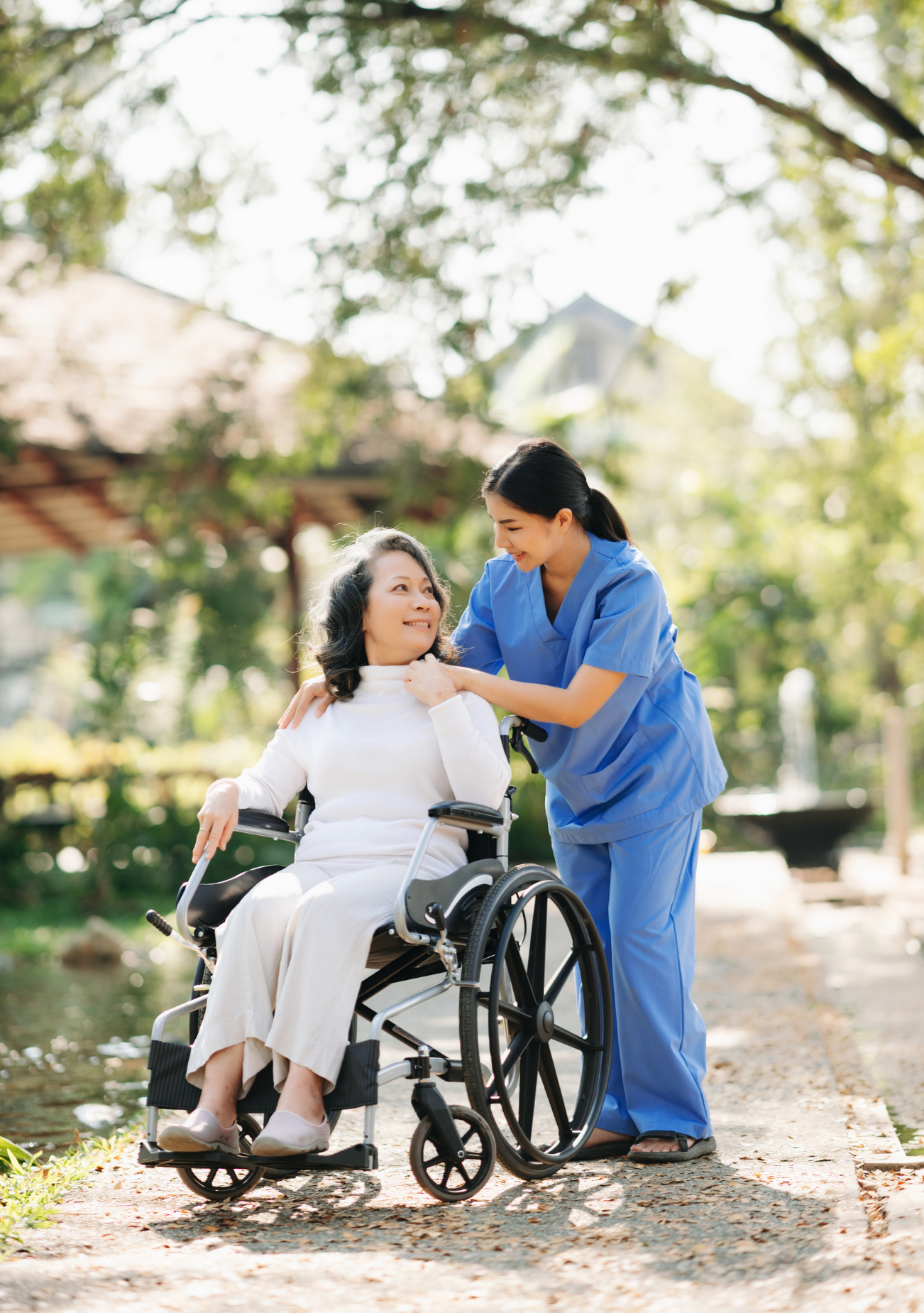 A nurse is helping an elderly woman in a wheelchair.