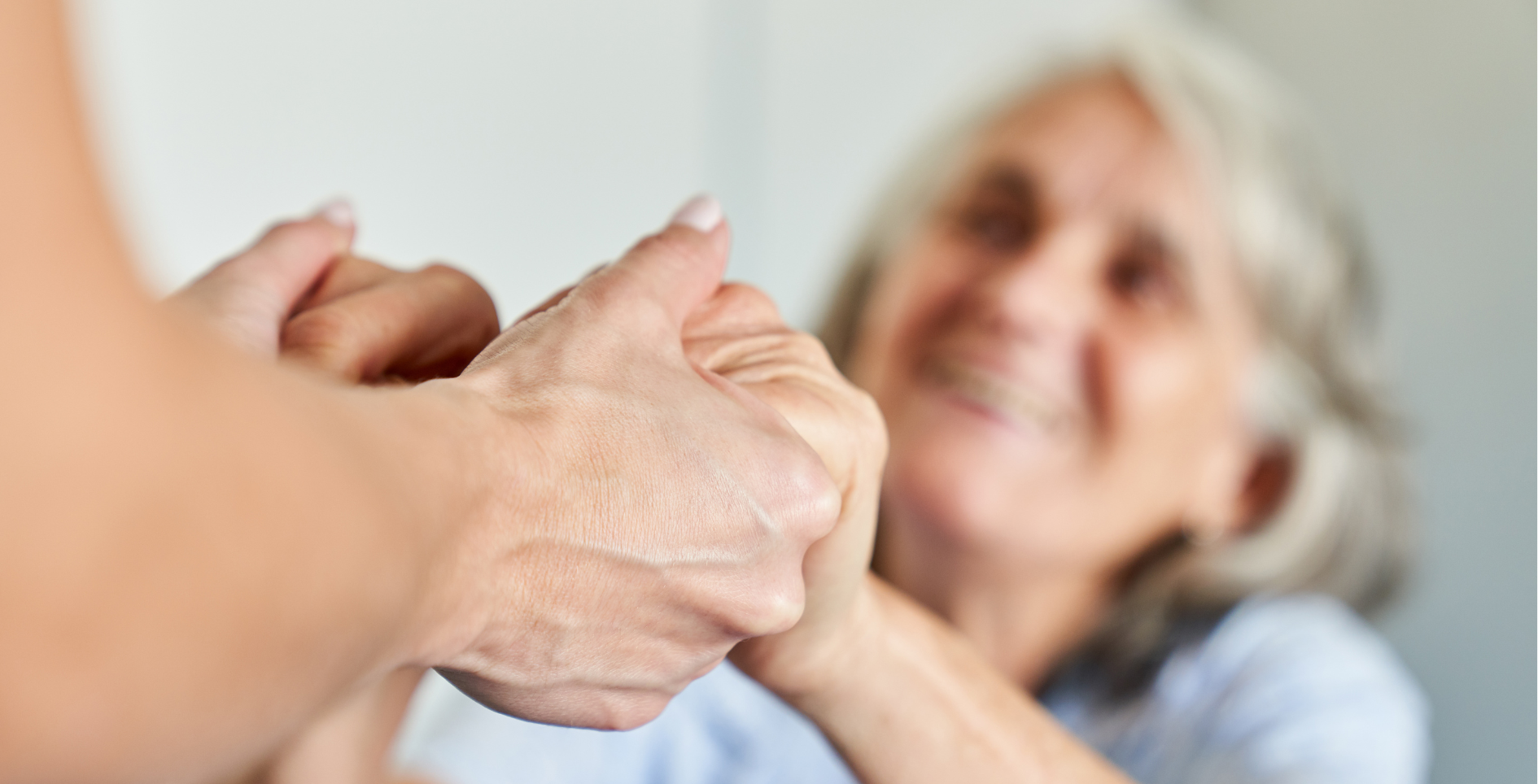 A woman is holding the hand of an older woman.