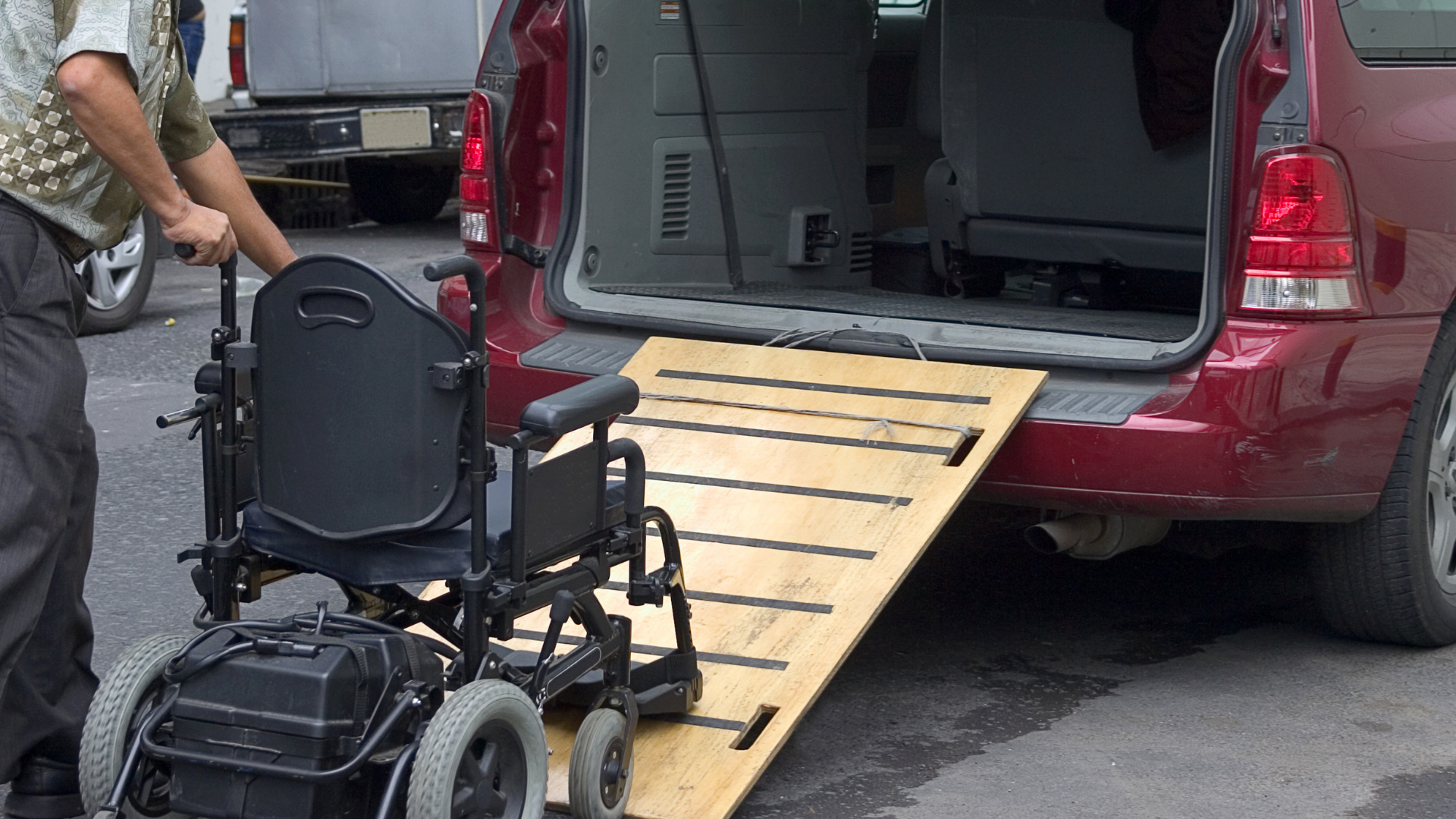 A man pushing a wheelchair into the back of a van