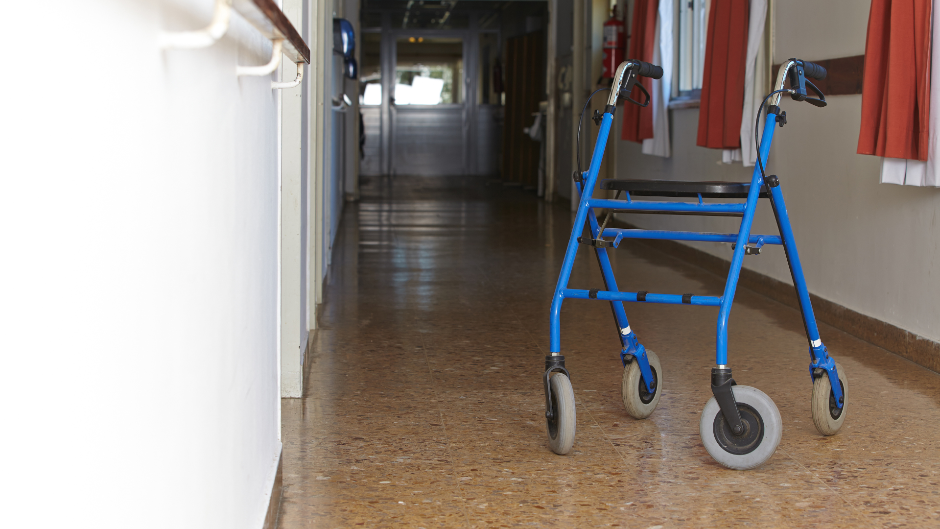 A blue walker is sitting in the middle of a hallway.