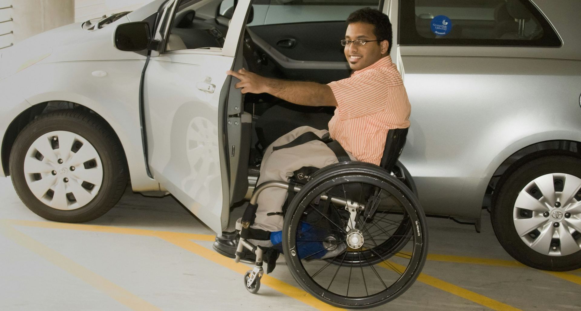 A man in a wheelchair is getting out of a car.