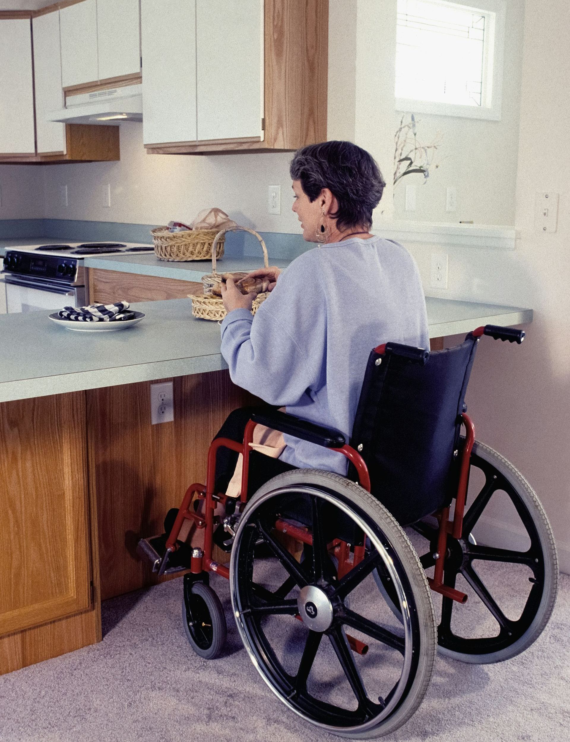 A woman in a wheelchair sits at a kitchen counter