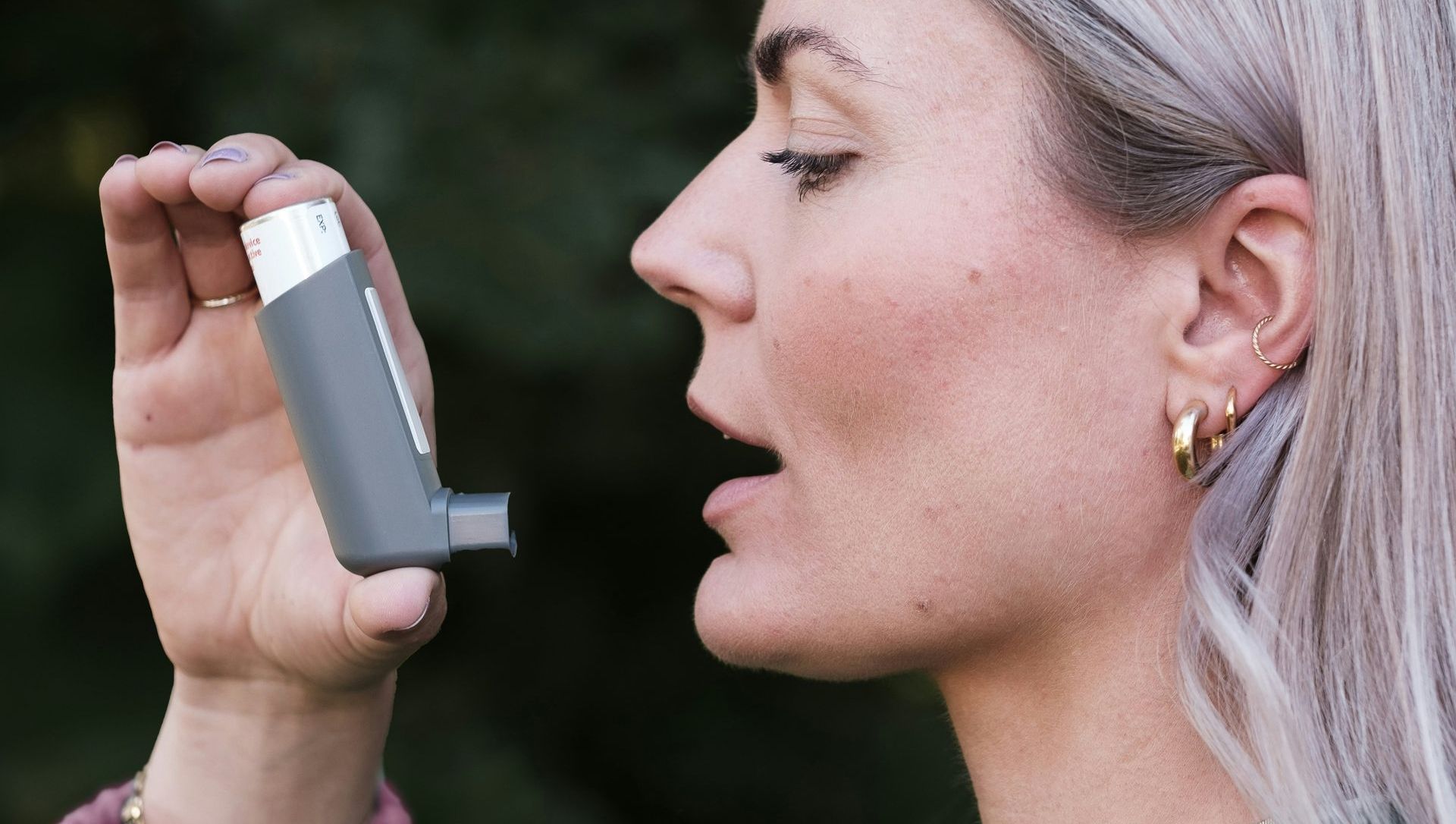 A woman is using an inhaler to treat her asthma.