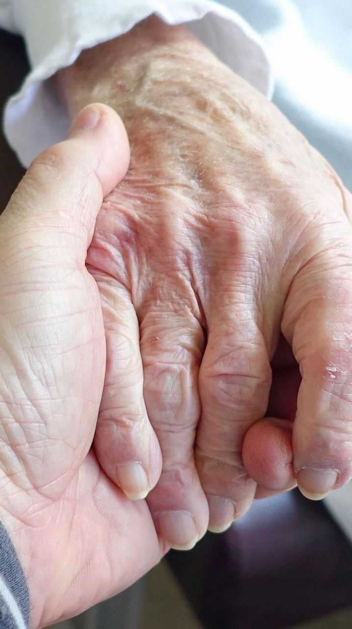 A close up of a person holding an older person 's hand.