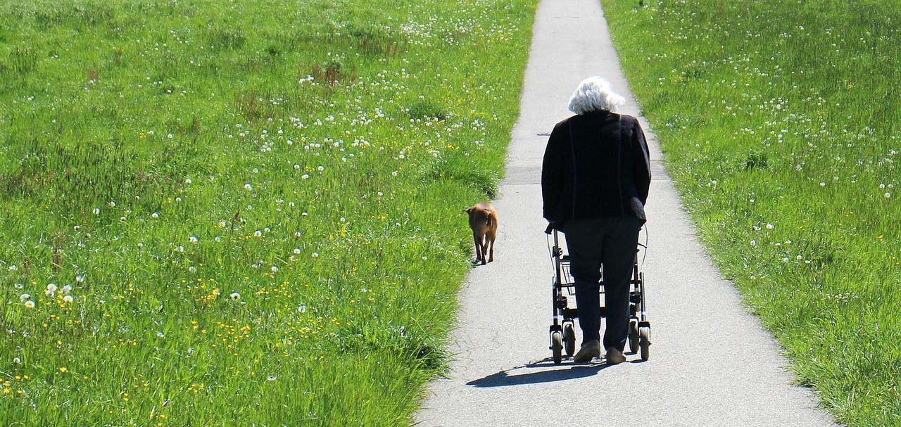 old woman using walker on path
