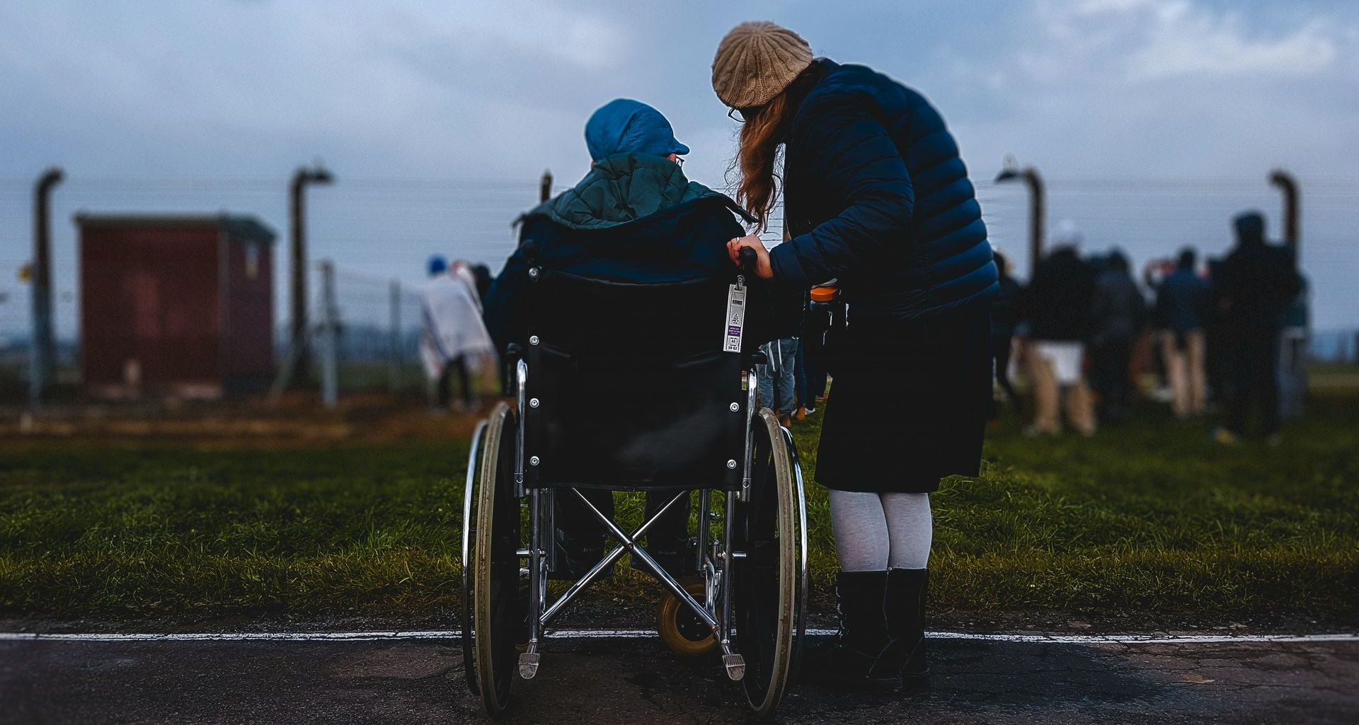 A woman is standing next to a man in a wheelchair.