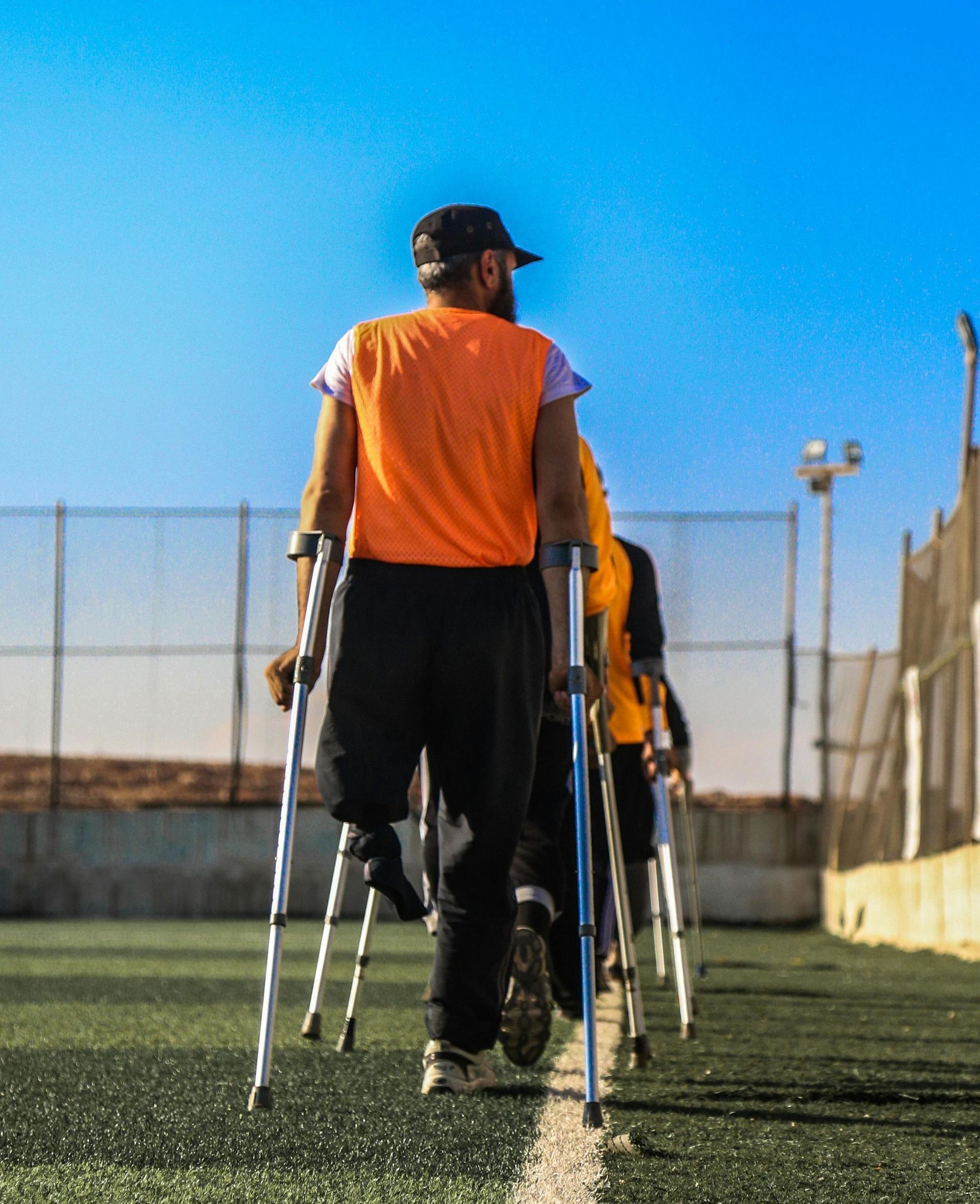 A man with crutches is walking on a field