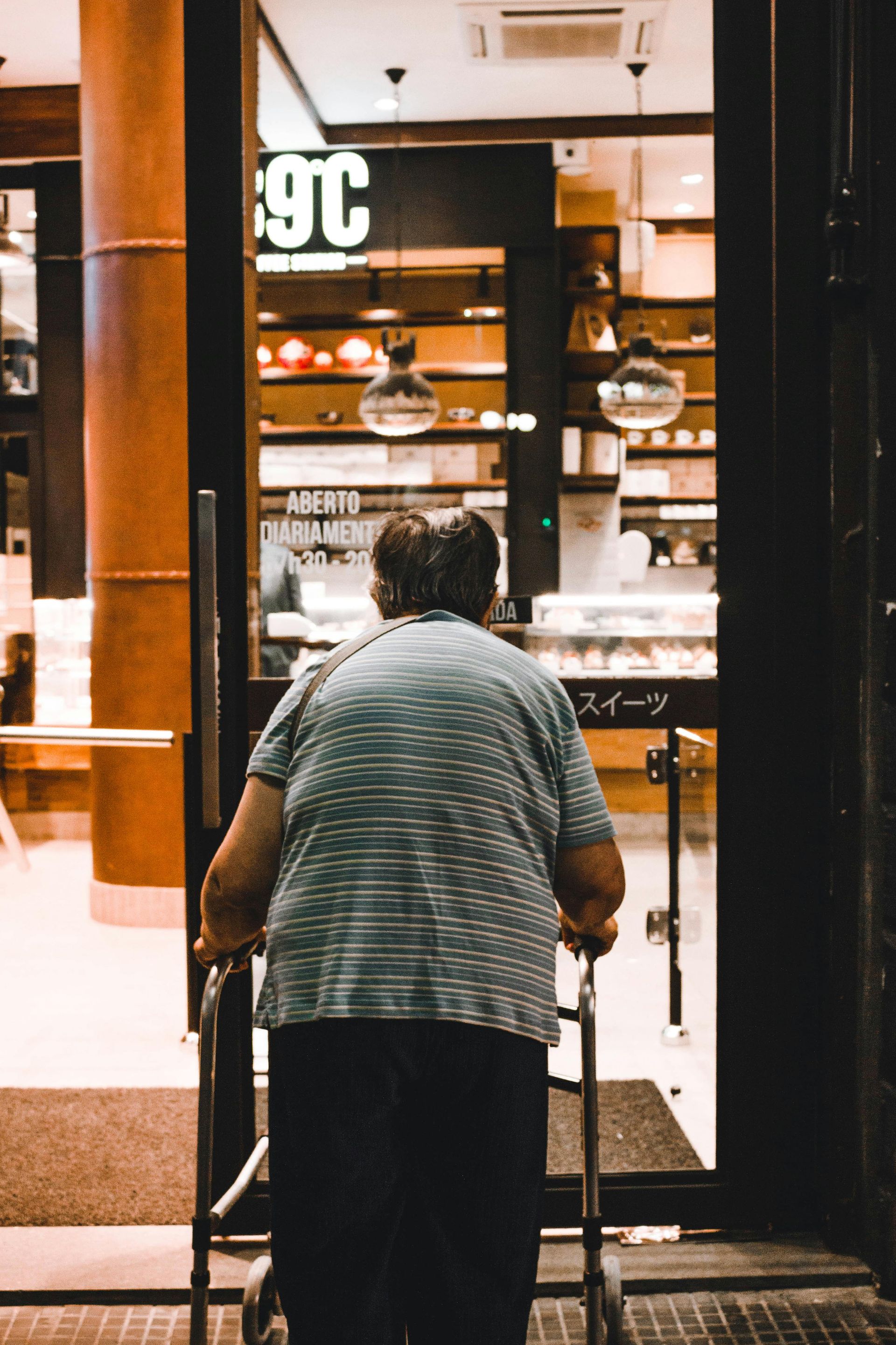 An elderly woman with a walker is walking into a store