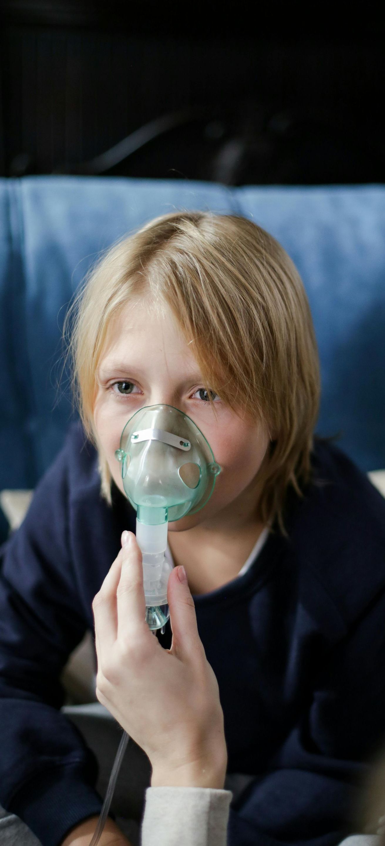 A young boy is wearing an oxygen mask on his face.