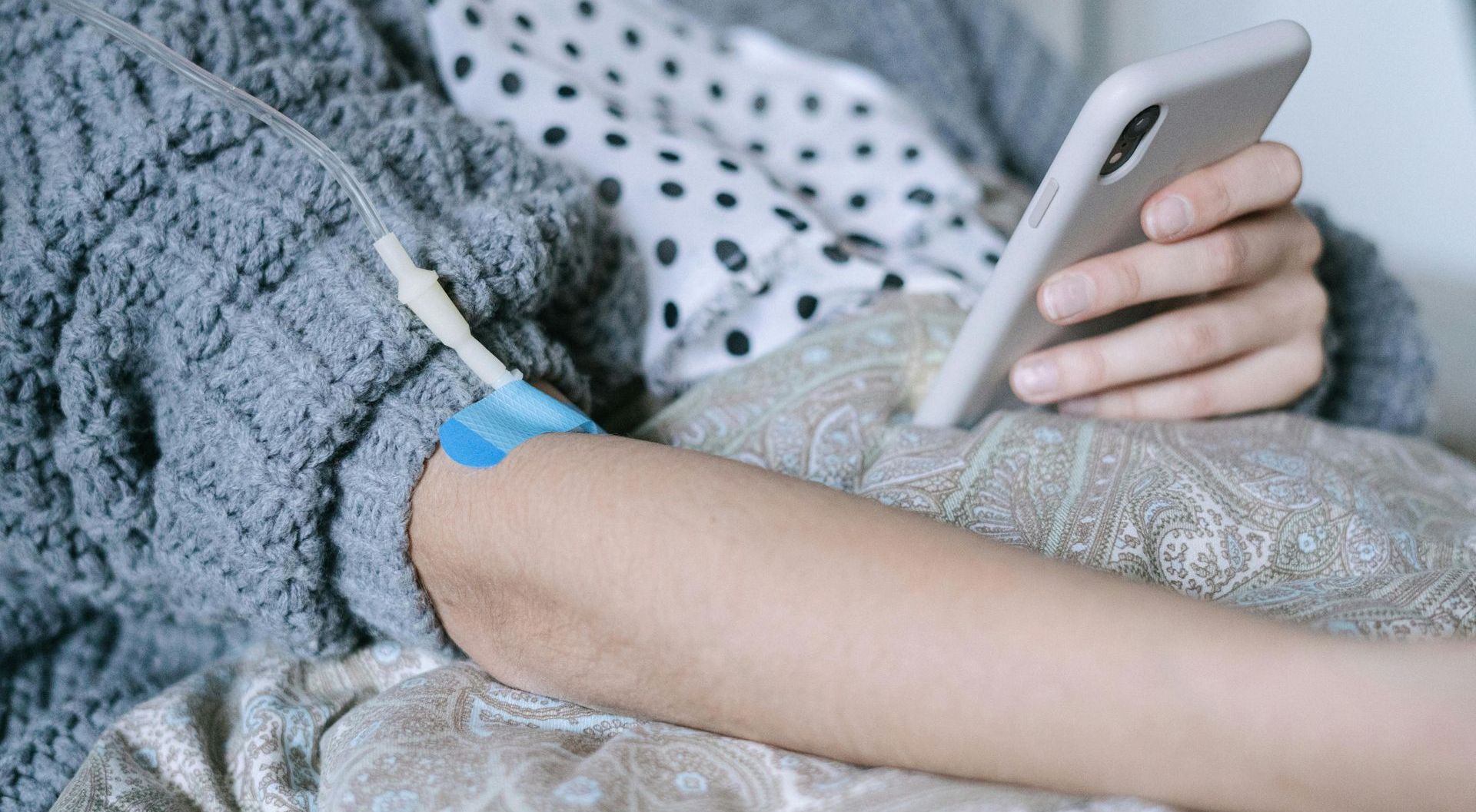 A woman is laying on a couch using a cell phone.