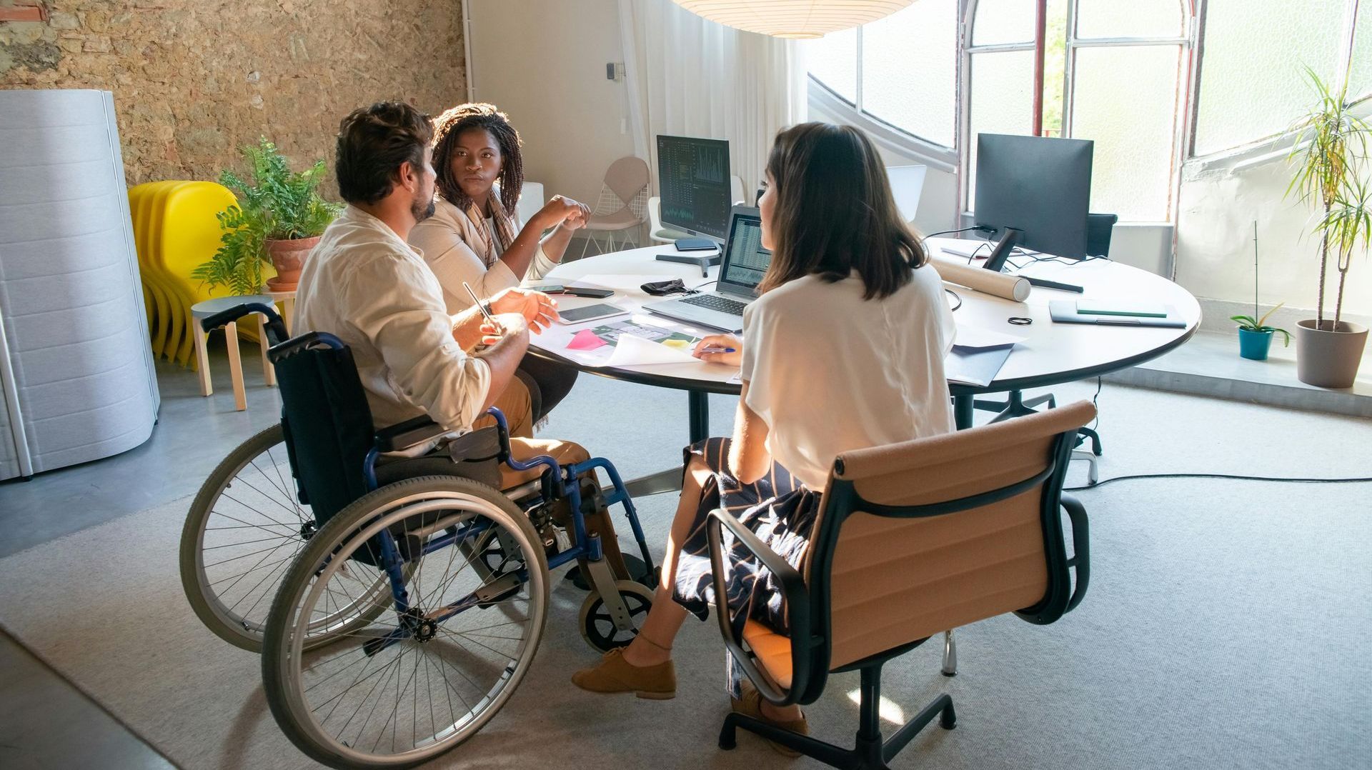 A man in a wheelchair is sitting at a table with two other people.