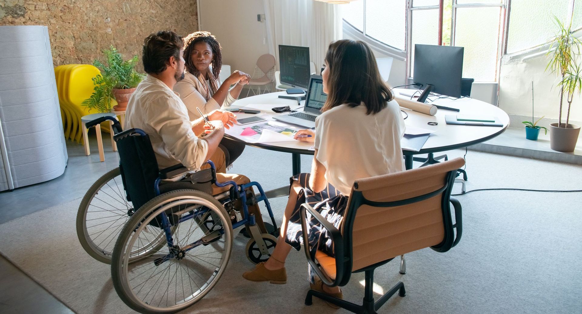 a man in a wheelchair is sitting at a table with two other people.