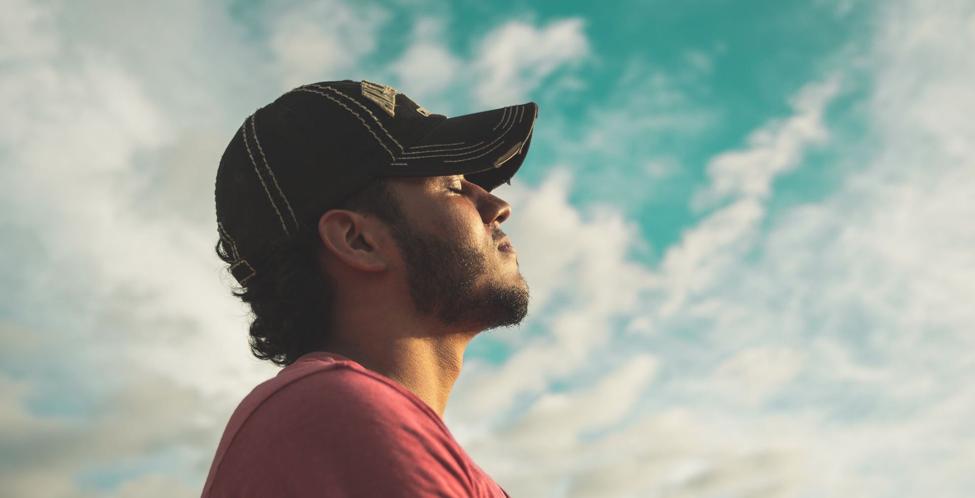 a man wearing a baseball cap is looking up at the sky.