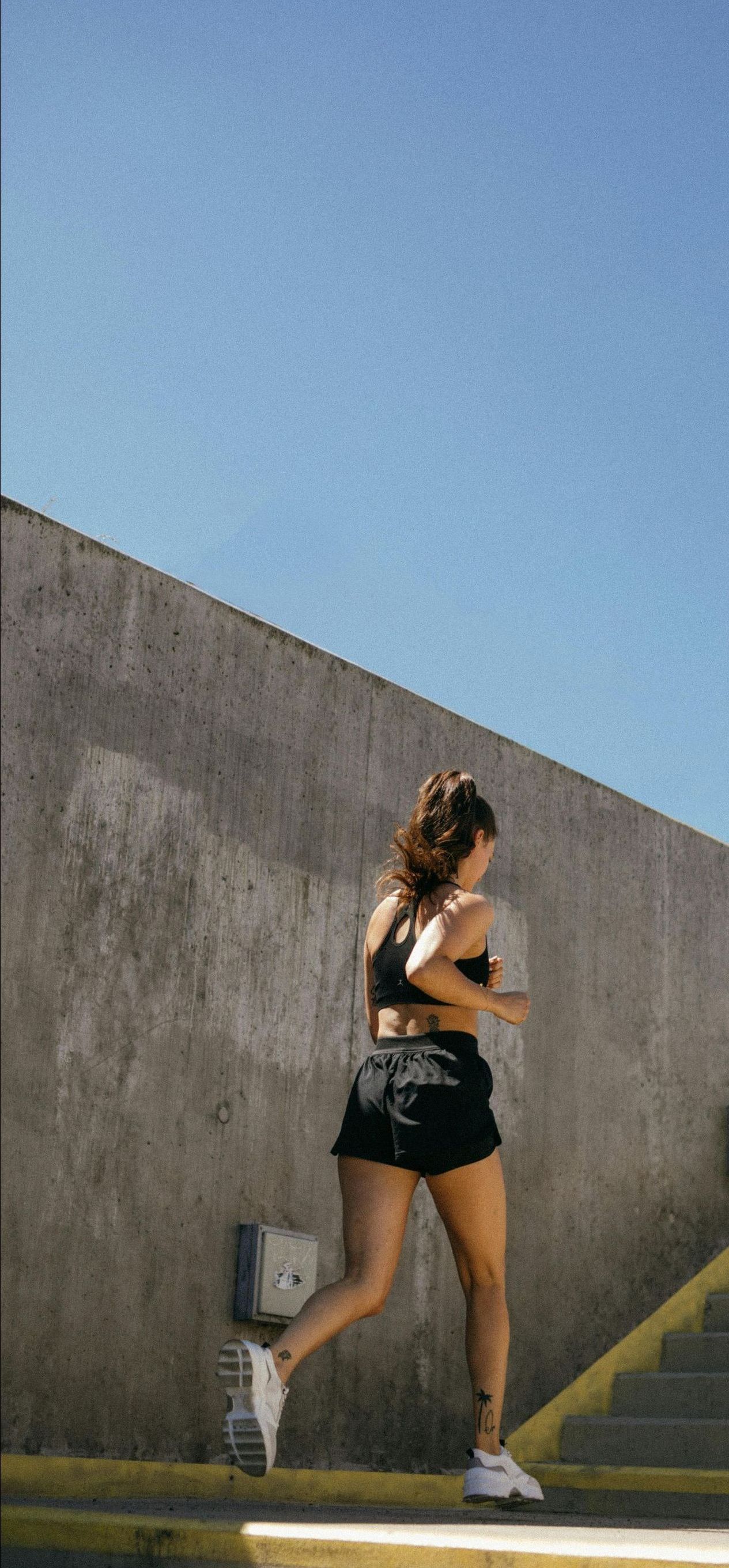 A woman is running up stairs in front of a wall.