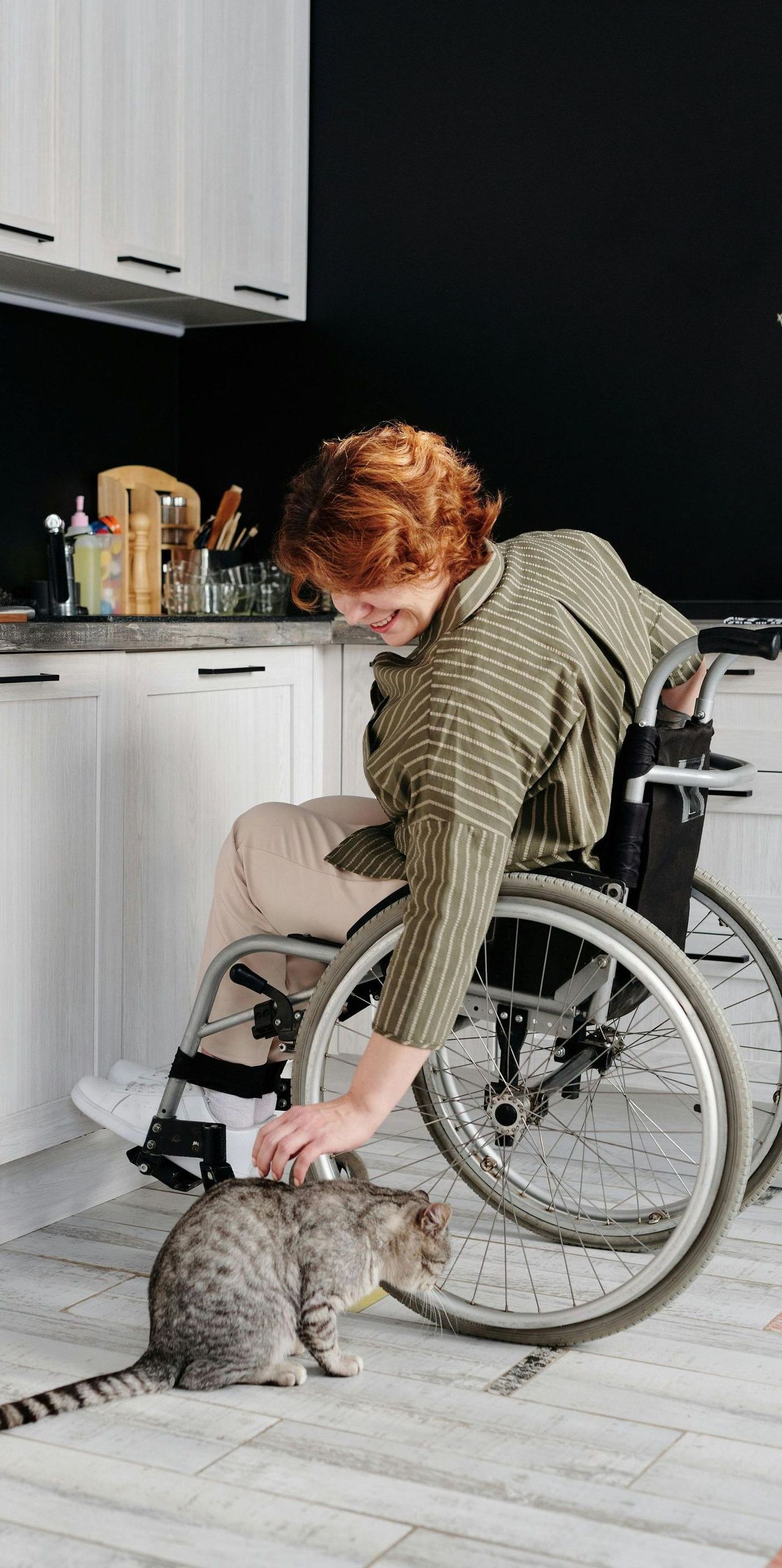 A woman is sitting in a wheelchair with her hand on the wheel.