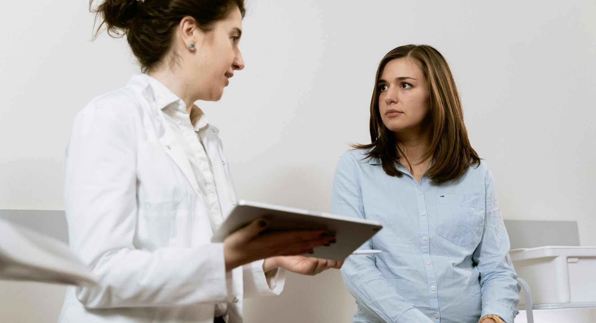 A doctor is talking to a patient while holding a tablet.