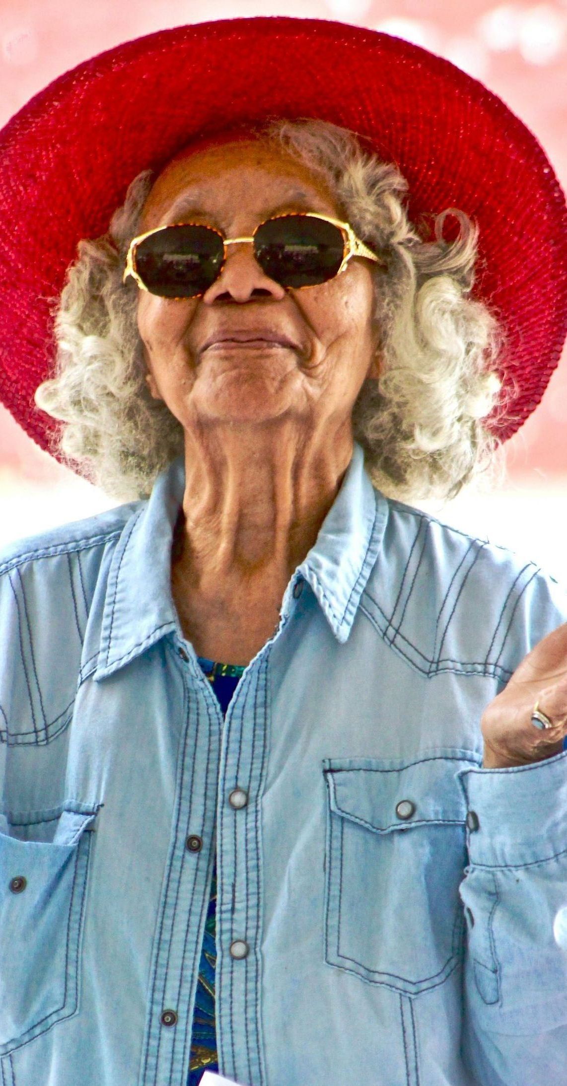 An elderly woman wearing a red hat and sunglasses.