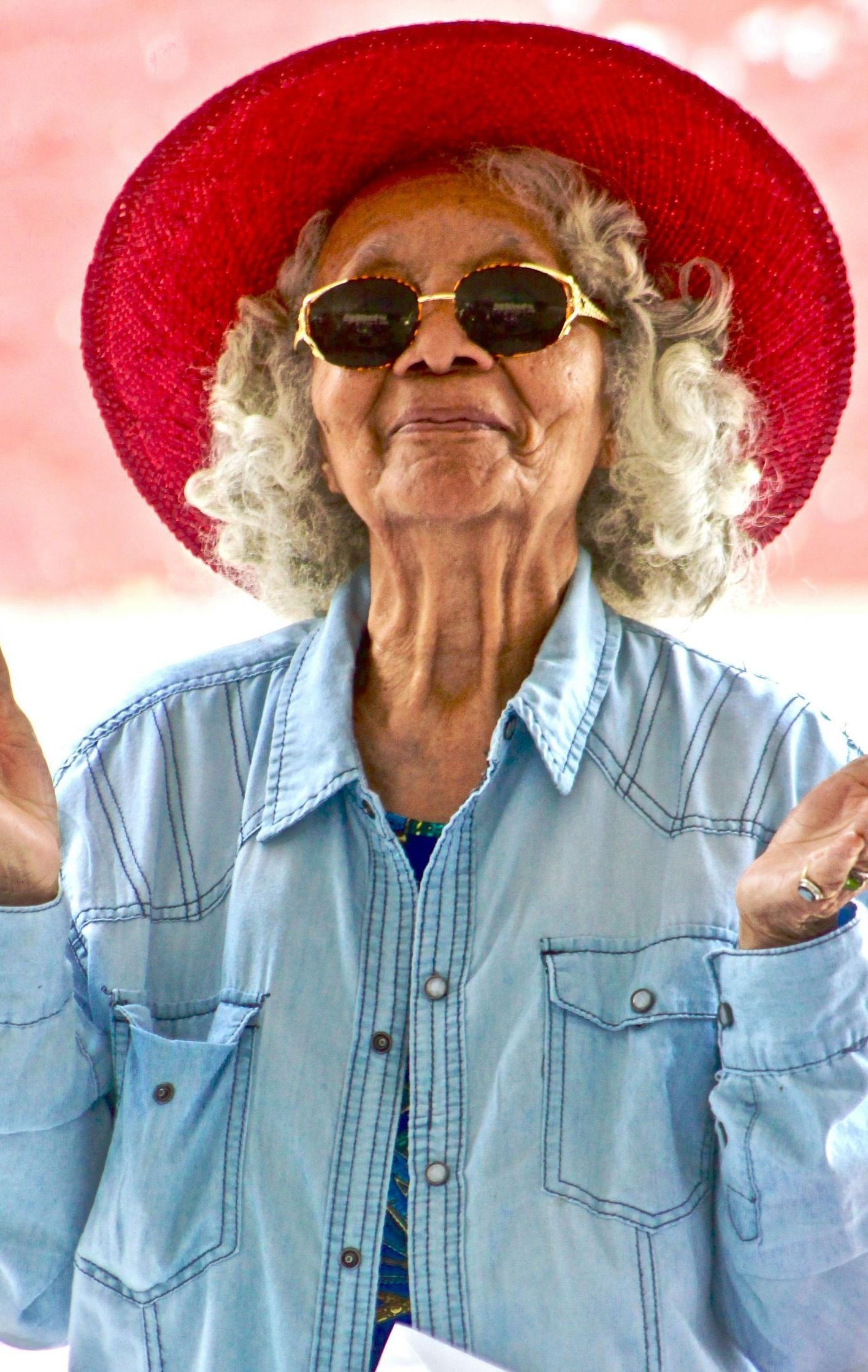 An elderly woman wearing a red hat and sunglasses