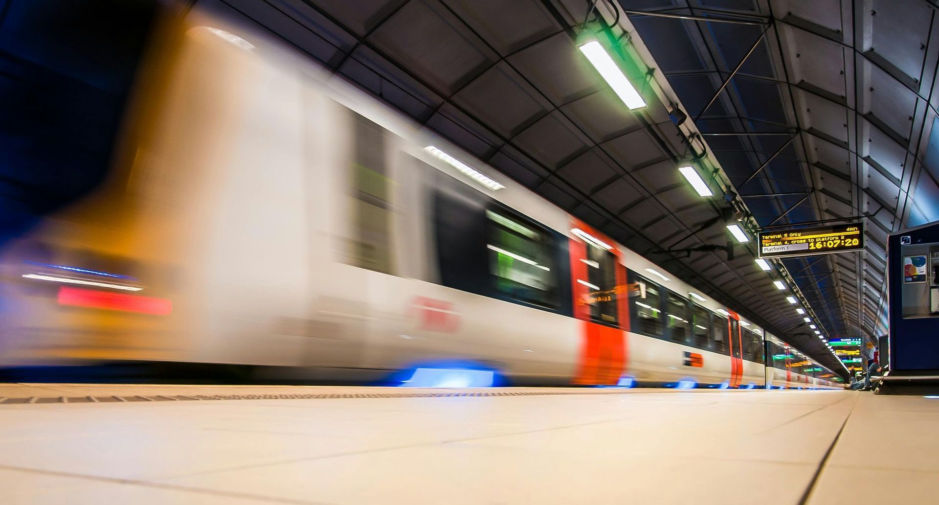 A train is pulling into a train station at night.