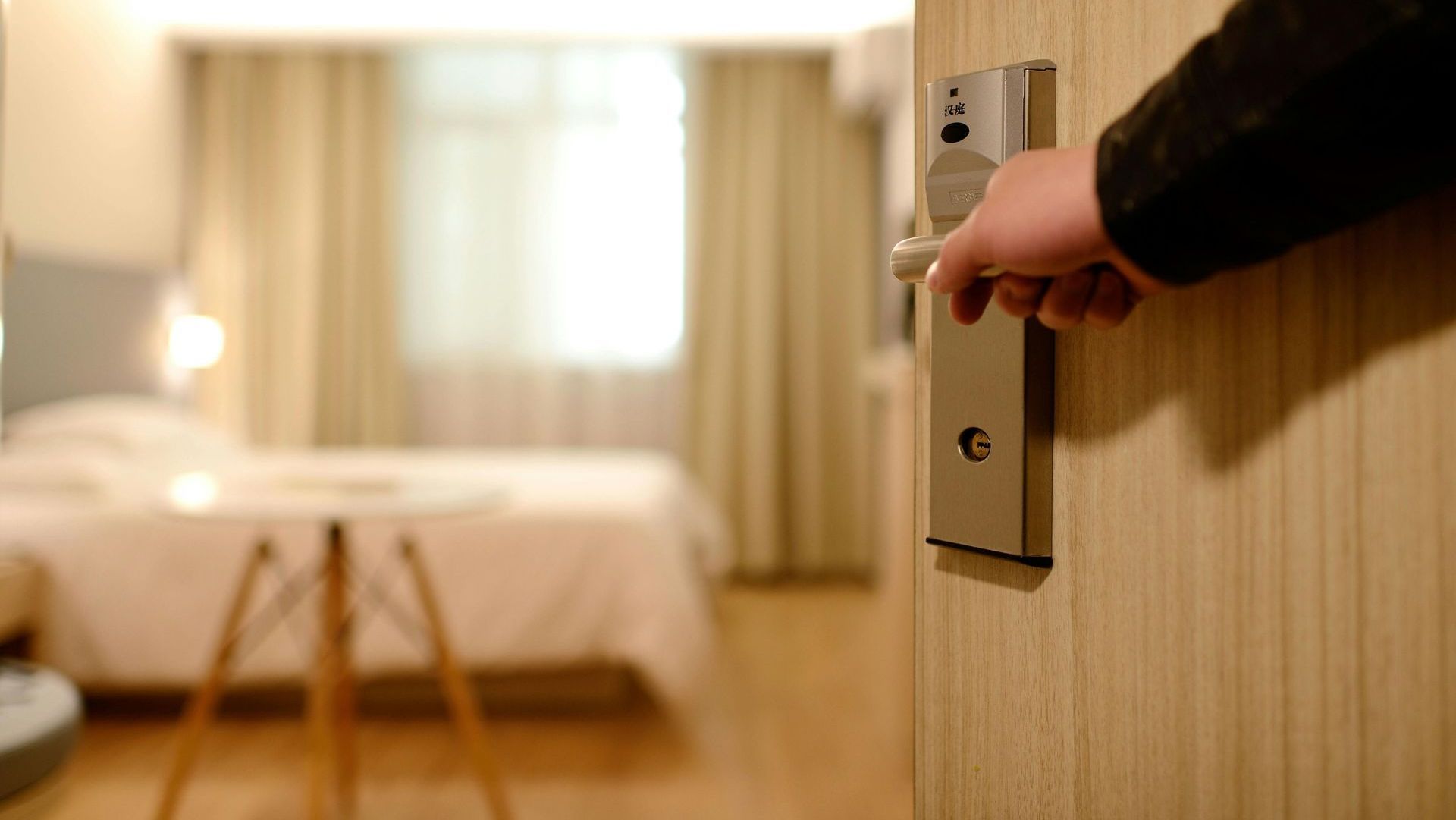 A person is opening a hotel room door with a key.