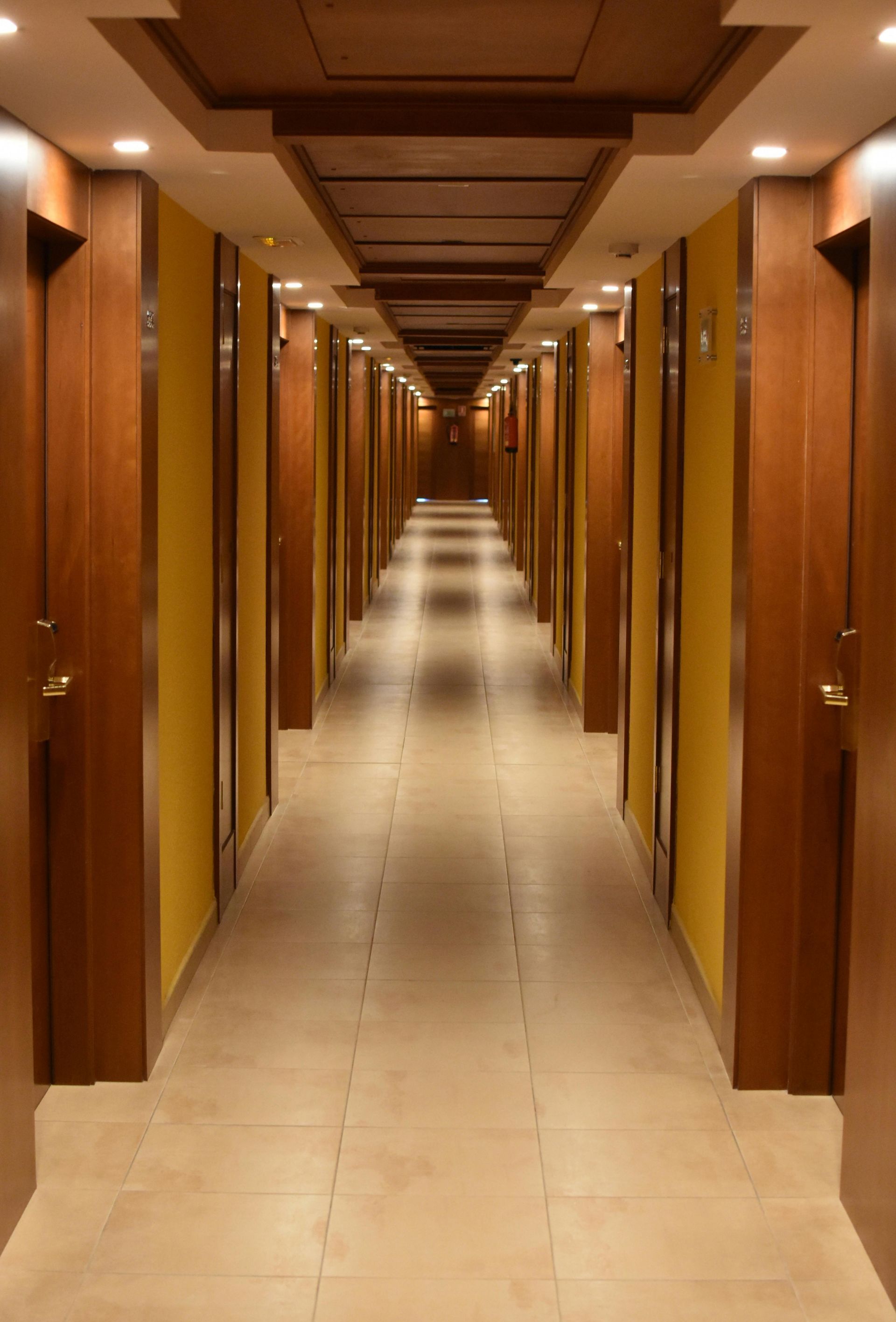 A long hallway with yellow walls and wooden doors