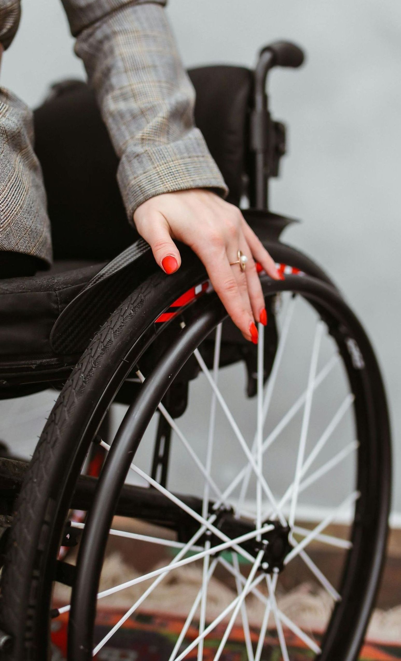 A woman is sitting in a wheelchair with her hand on the wheel.