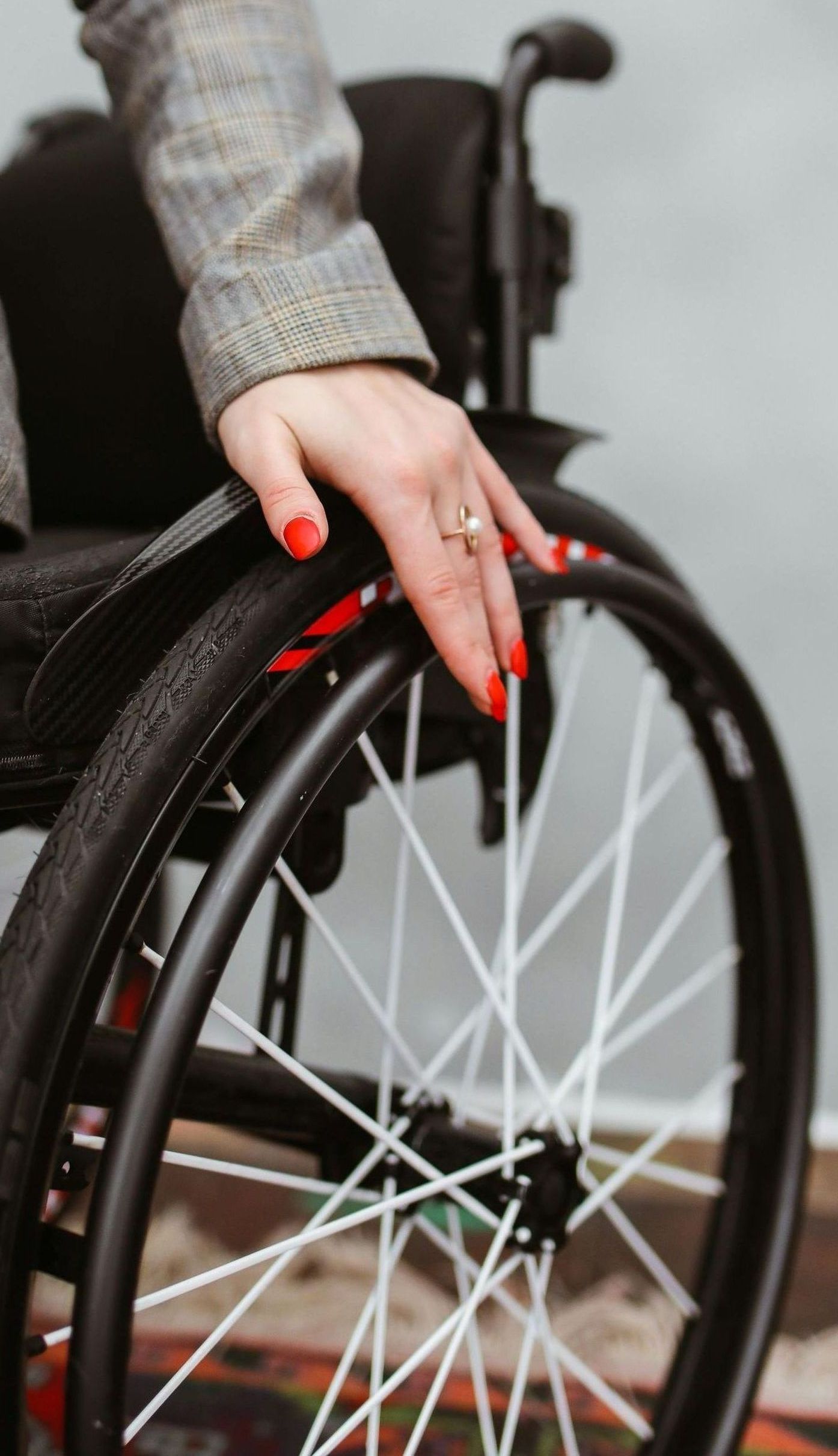 A woman is sitting in a wheelchair with her hand on the wheel.