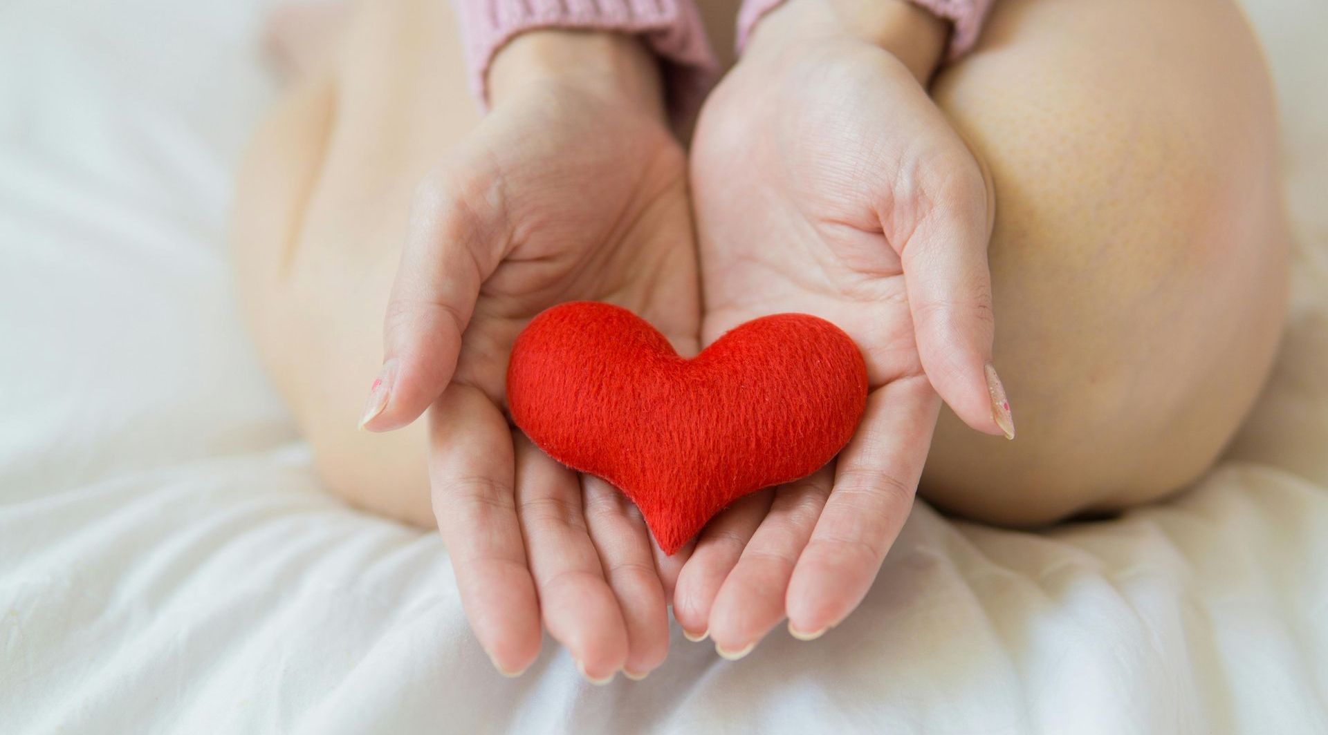 A woman is holding a red heart in her hands.