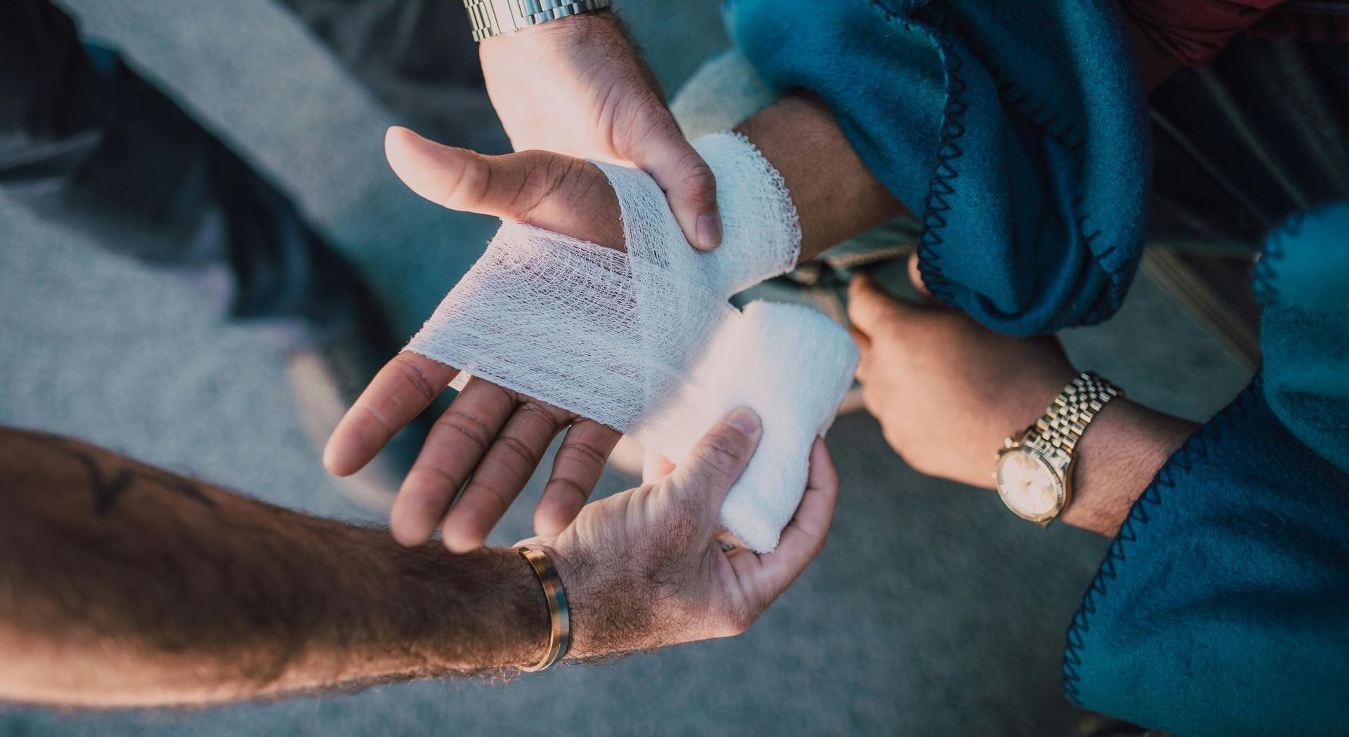 A person is wrapping another person 's hand with a bandage.