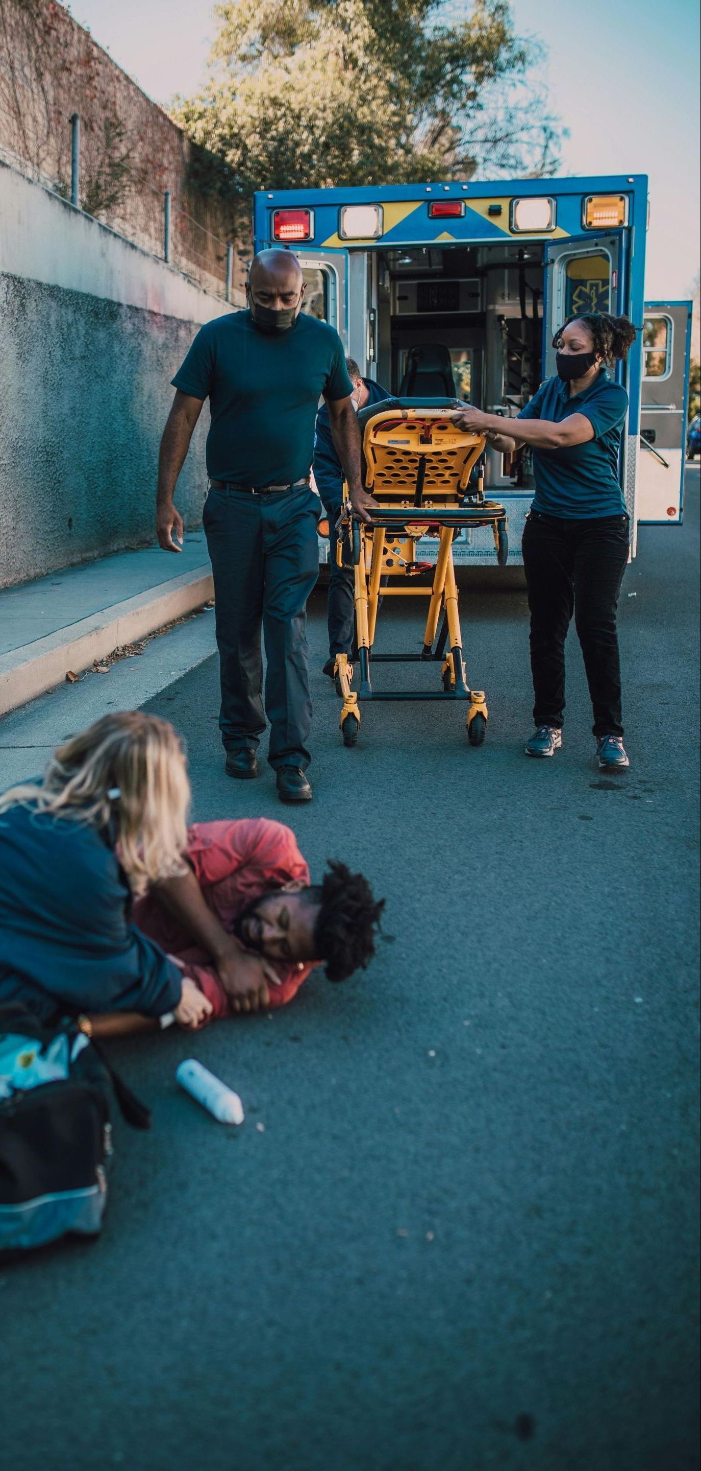 A man is laying on the ground with an ambulance in the background.