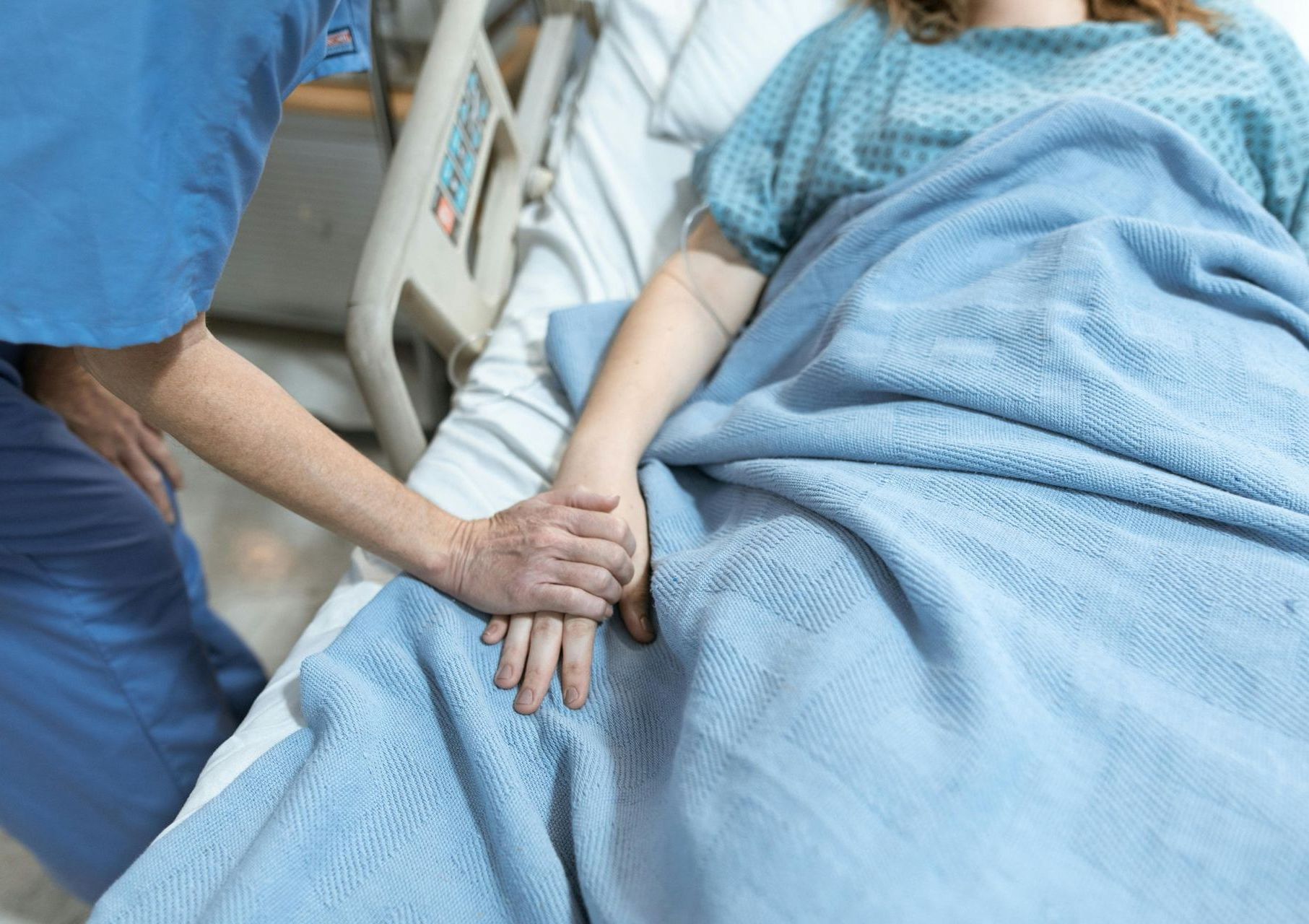 a nurse is holding the hand of a patient in a hospital bed 