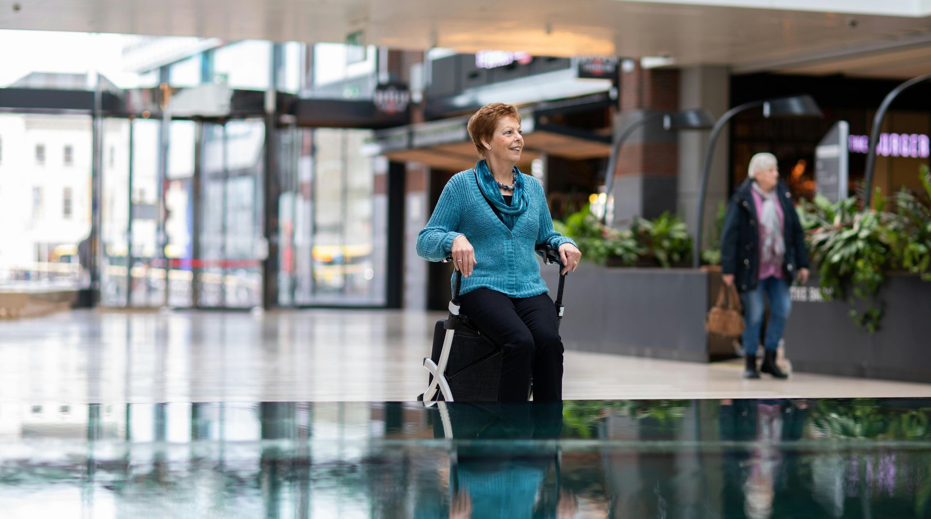 A woman is sitting in a wheelchair in a mall.