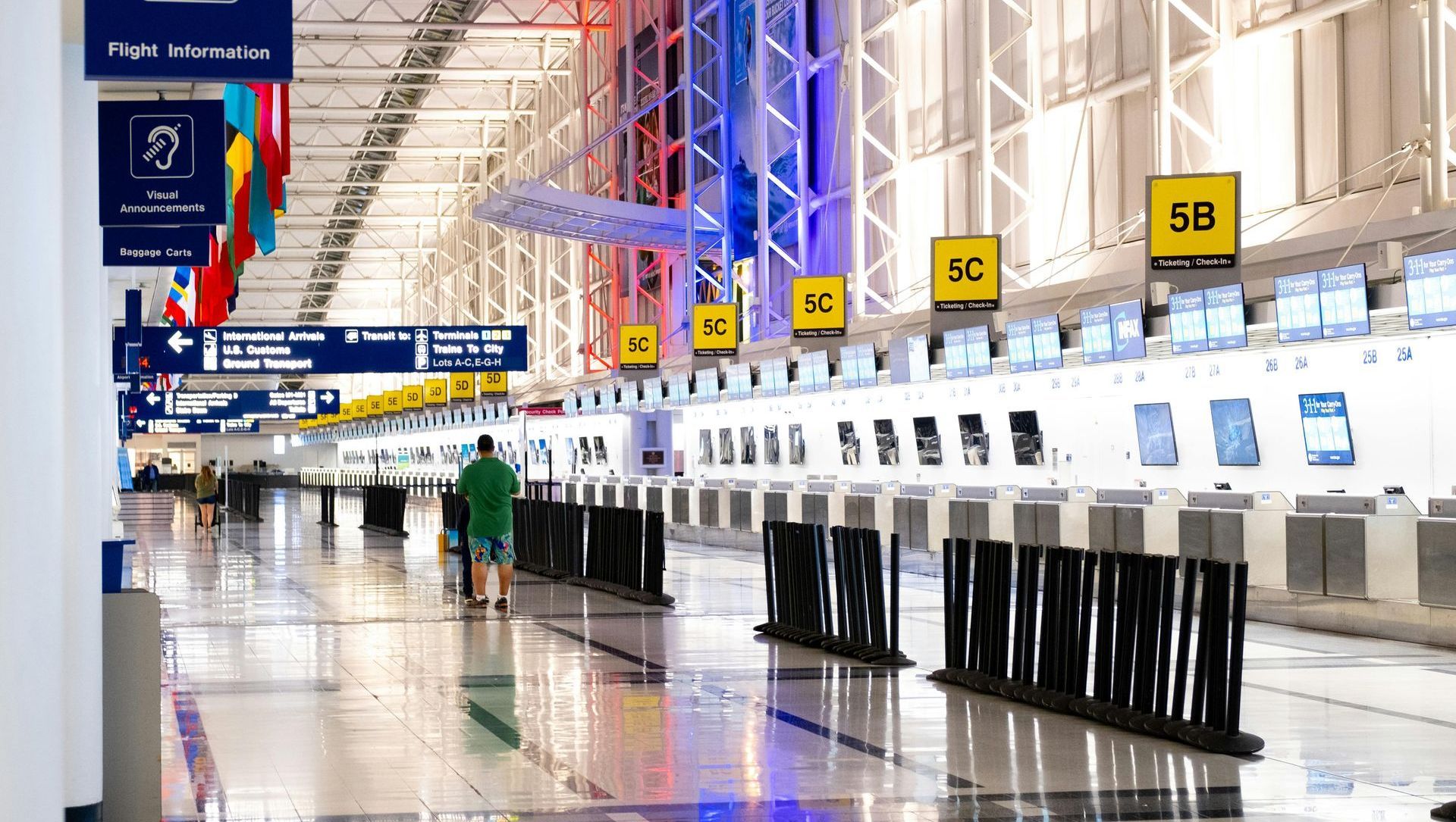 A man is walking through an empty airport terminal.