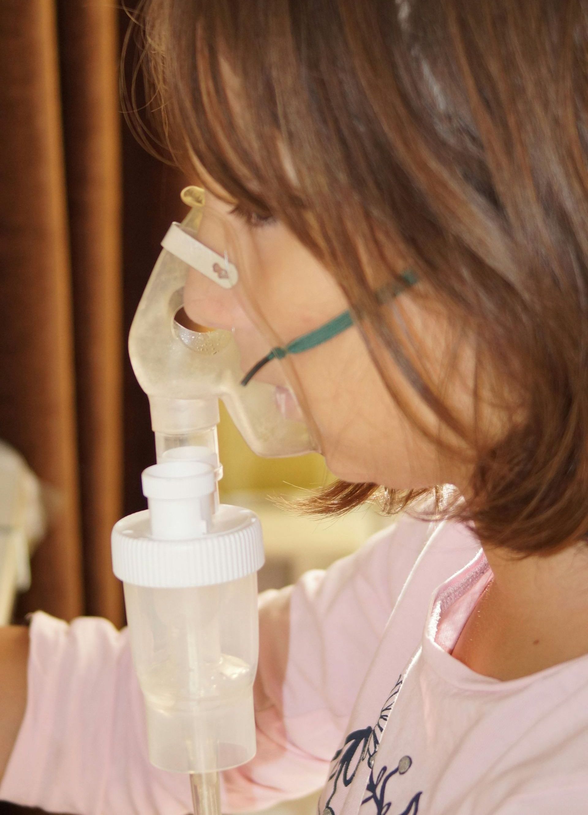 A little girl is wearing an oxygen mask on her face