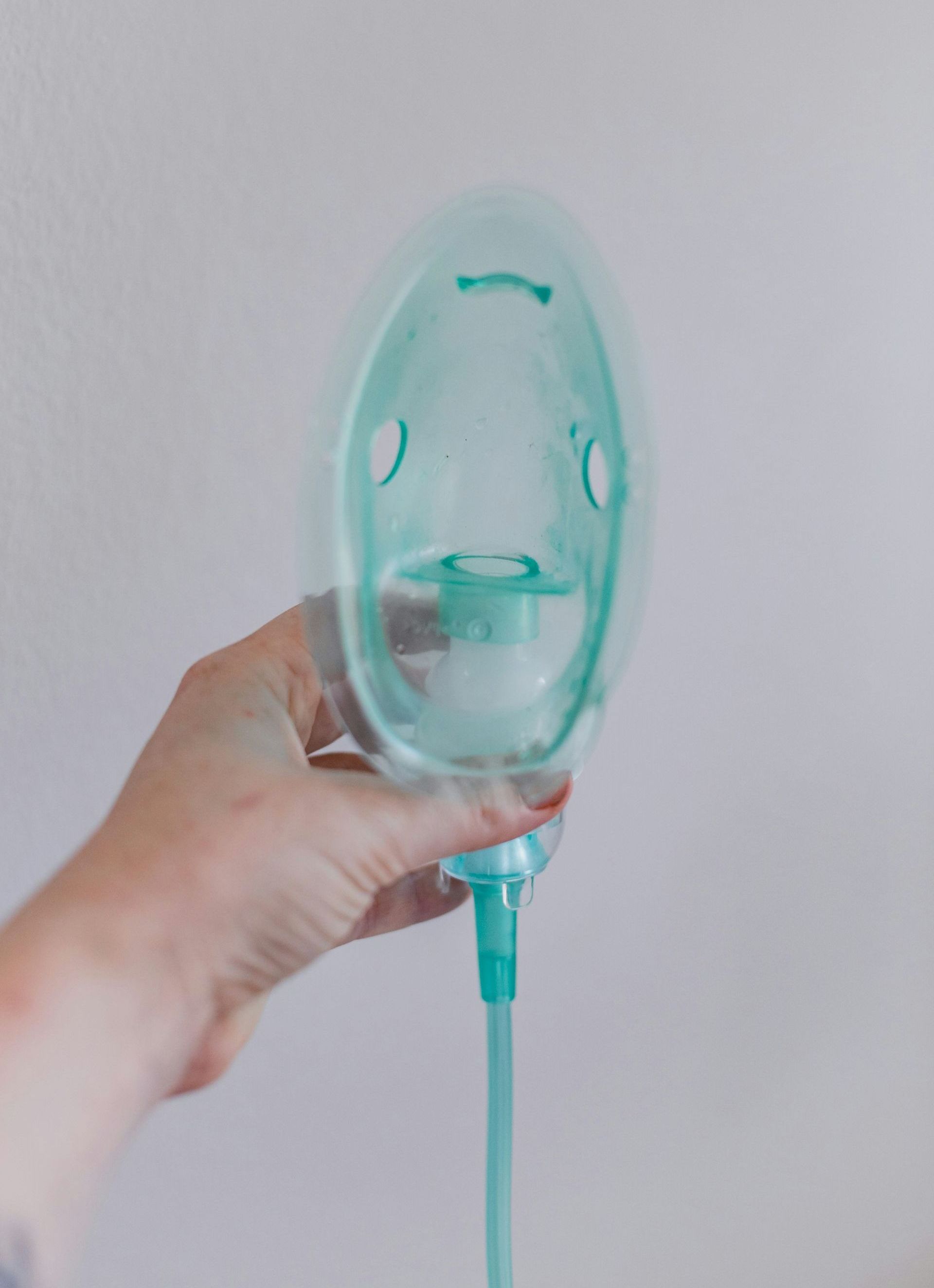 A person is holding an oxygen mask in their hand.