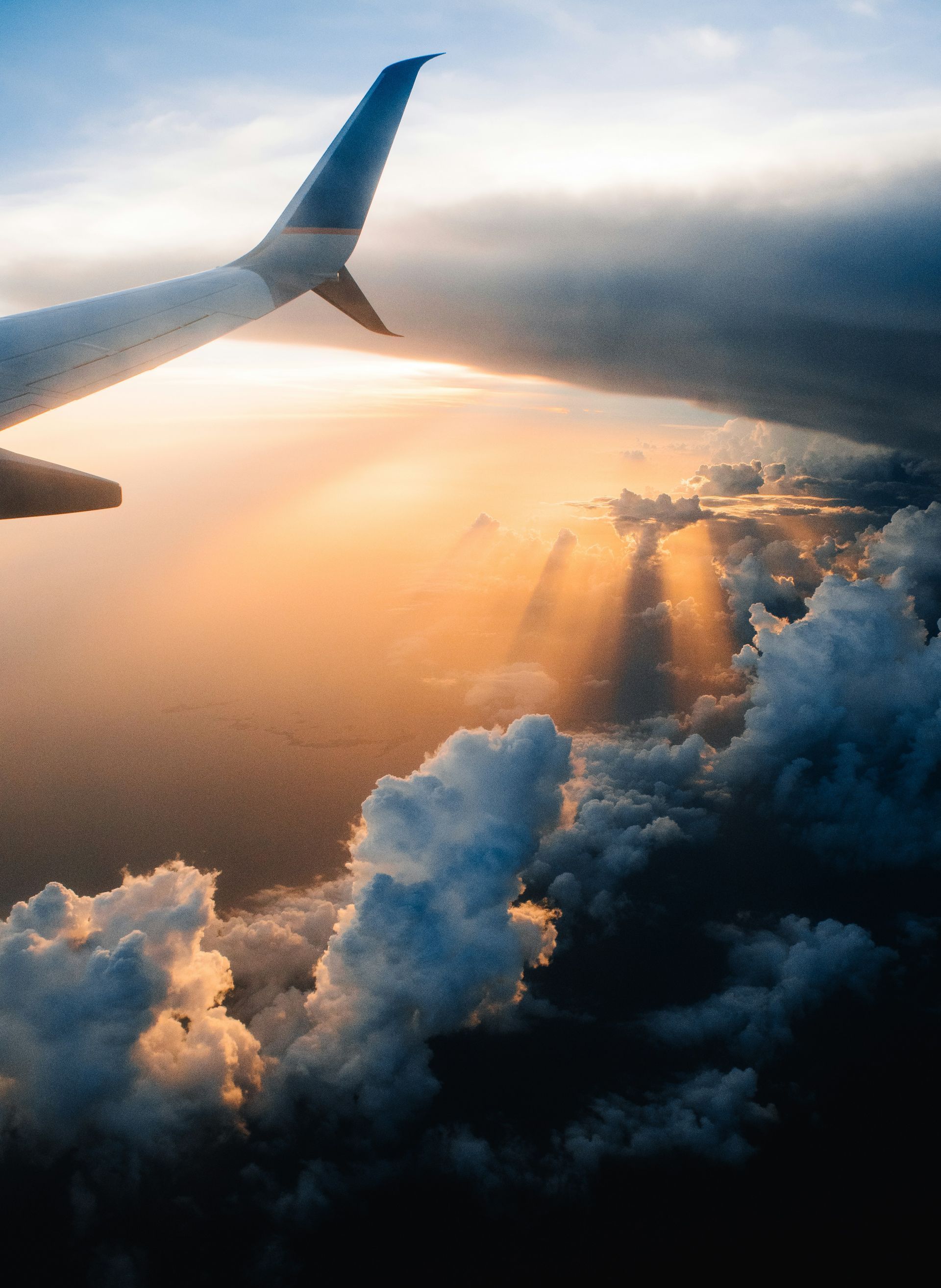 A plane is flying through the clouds at sunset.