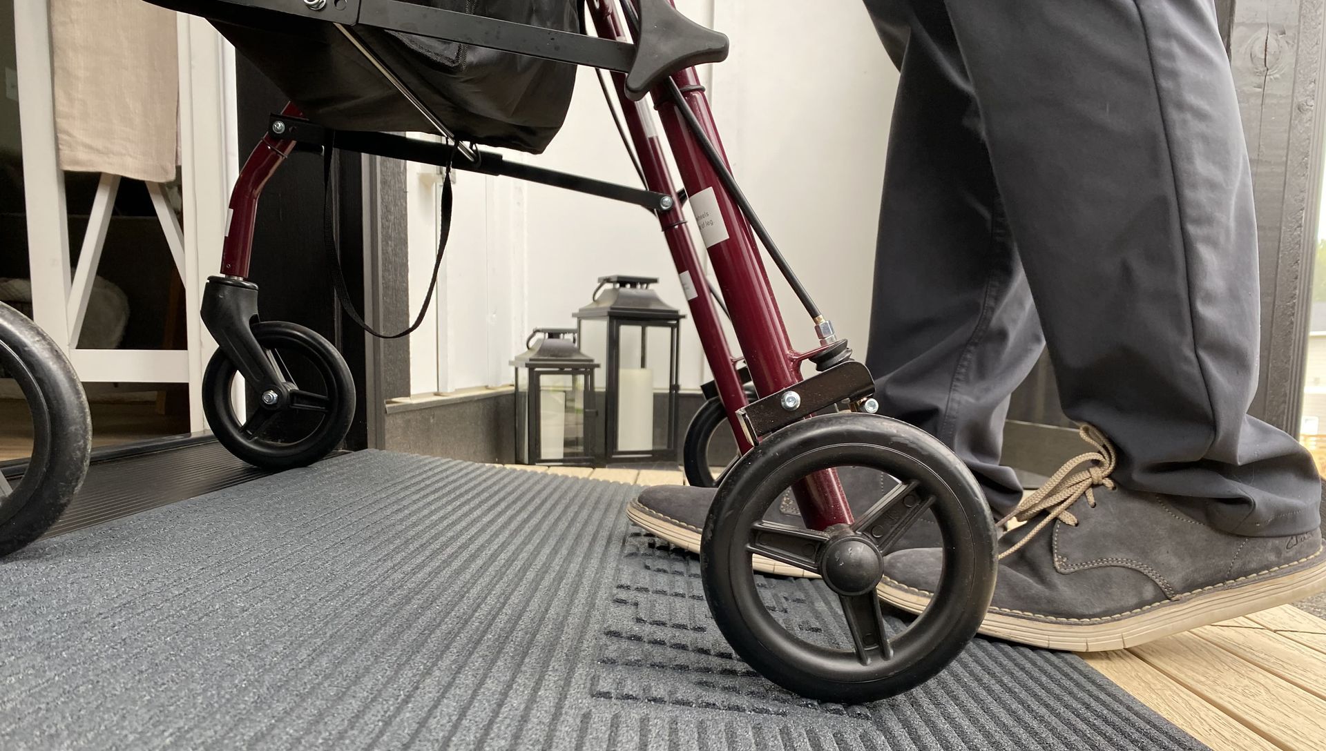 A person is standing next to a walker on a mat.