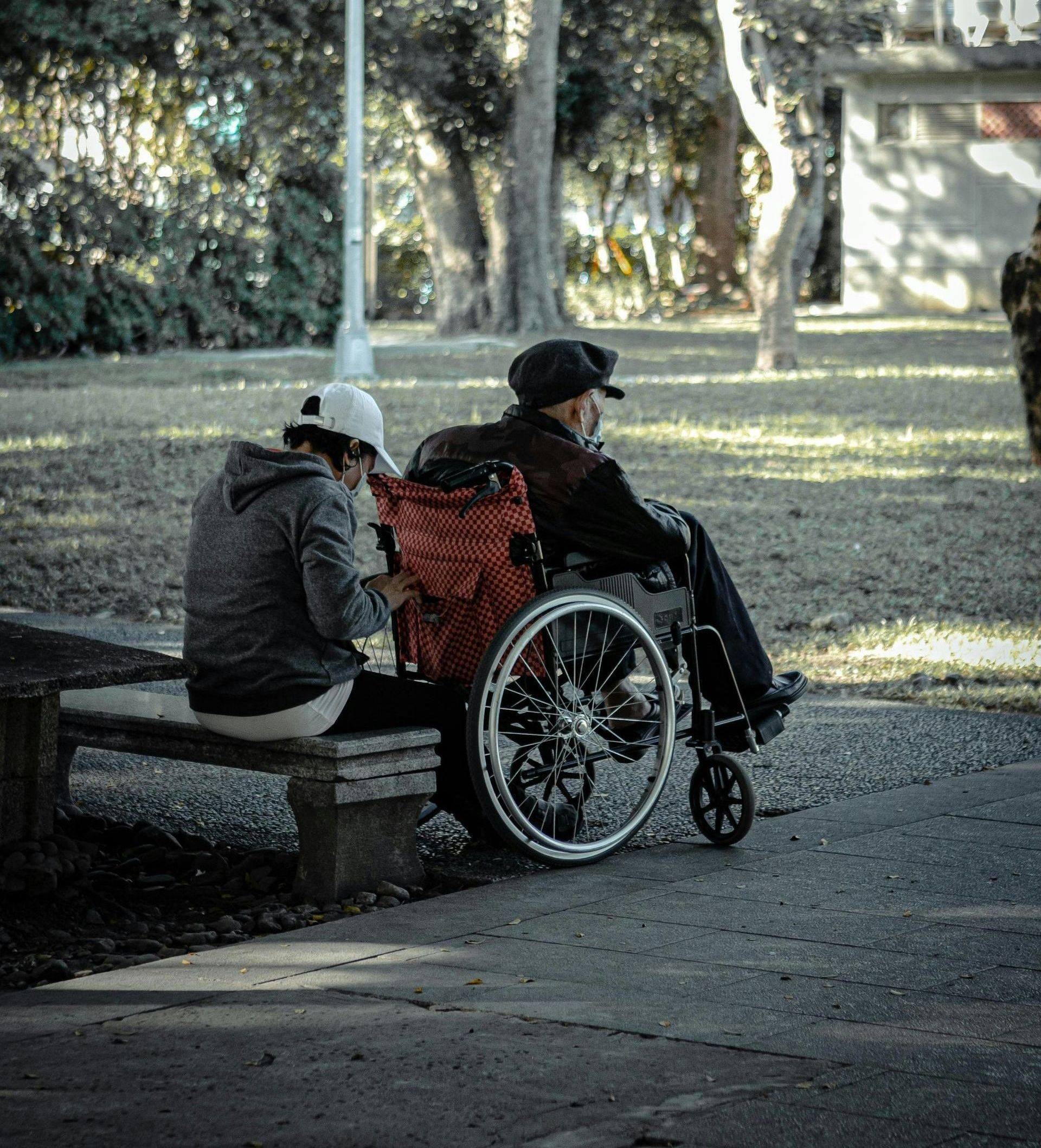 a man in a wheelchair is sitting on a bench next to a woman 