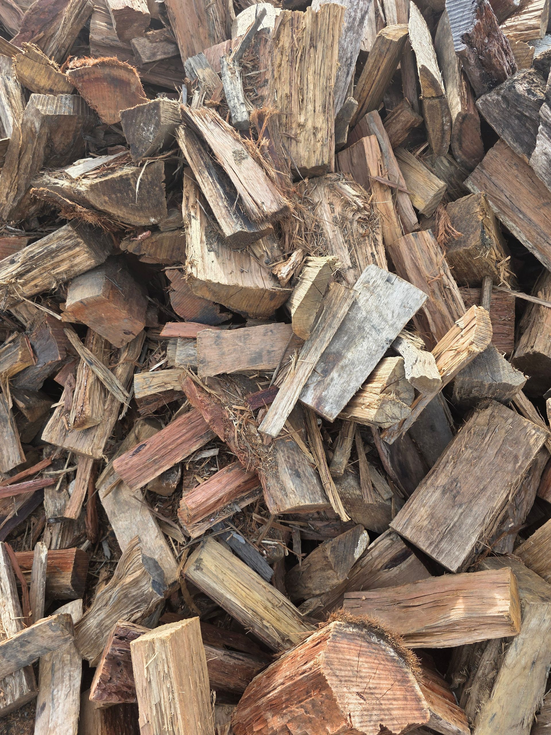 Close-up of brown and reddish-brown wood chips scattered randomly, likely for garden use.